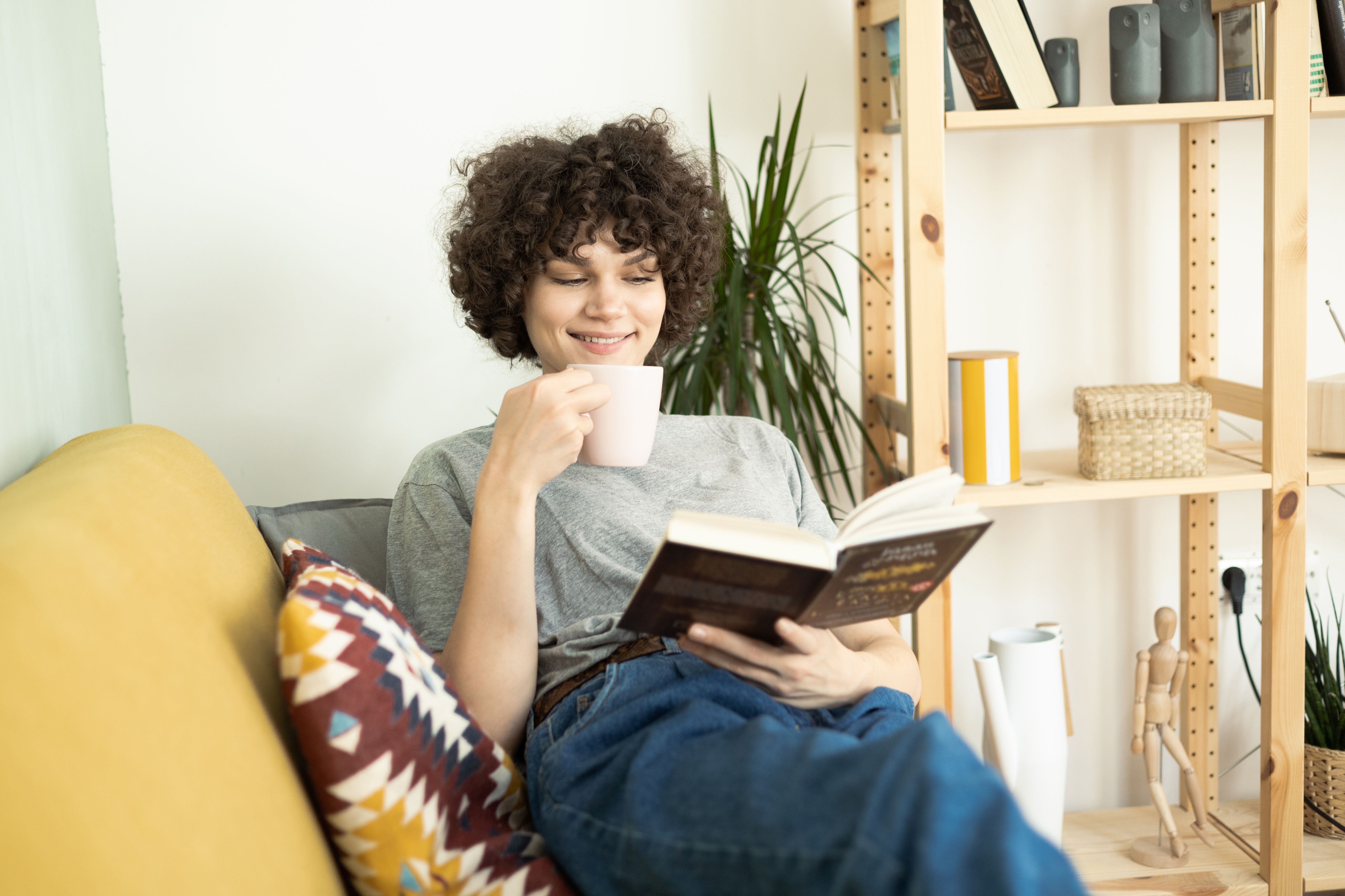 Fille heureuse appréciant le café et lisant à la maison