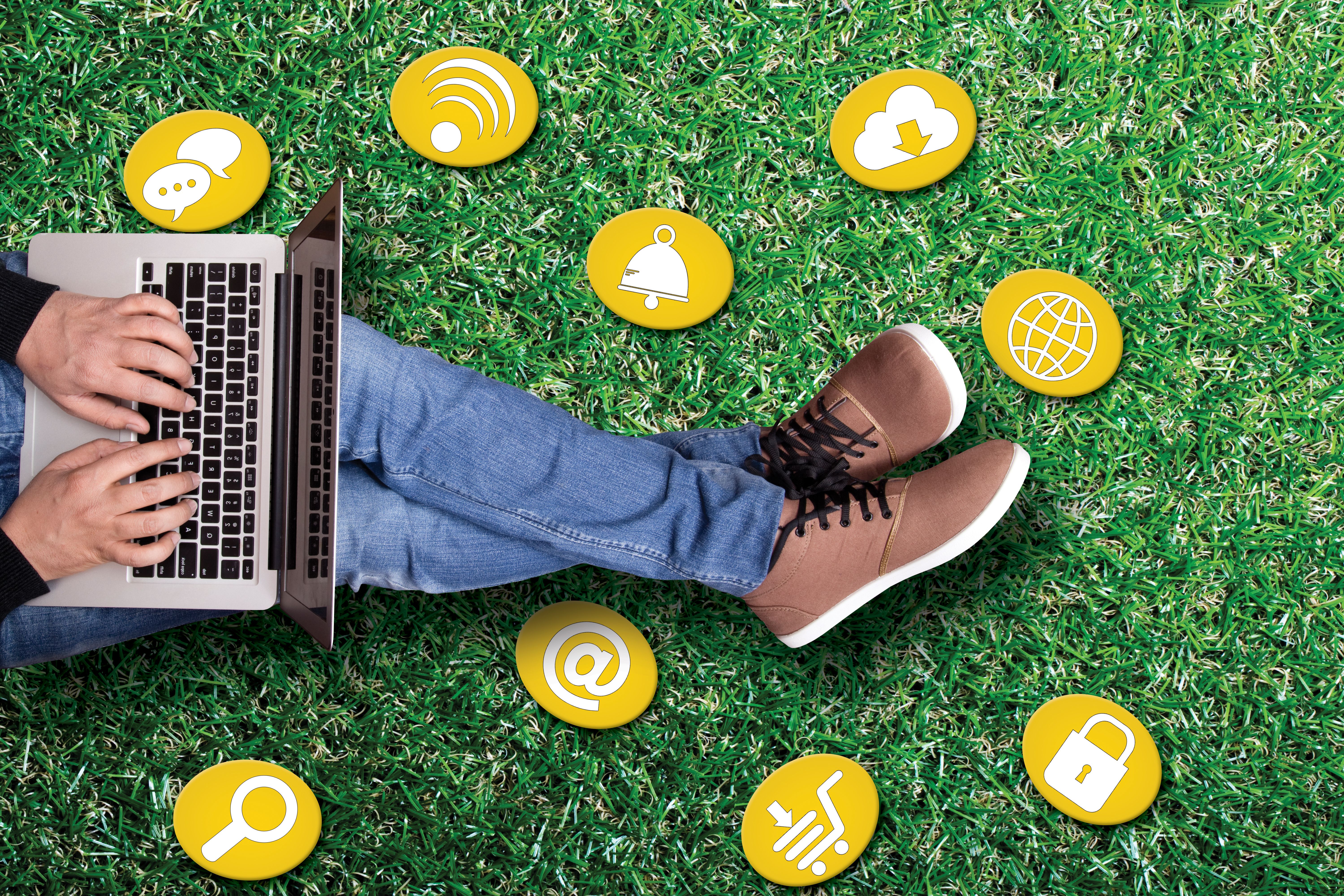 Man using laptop with icons on grass