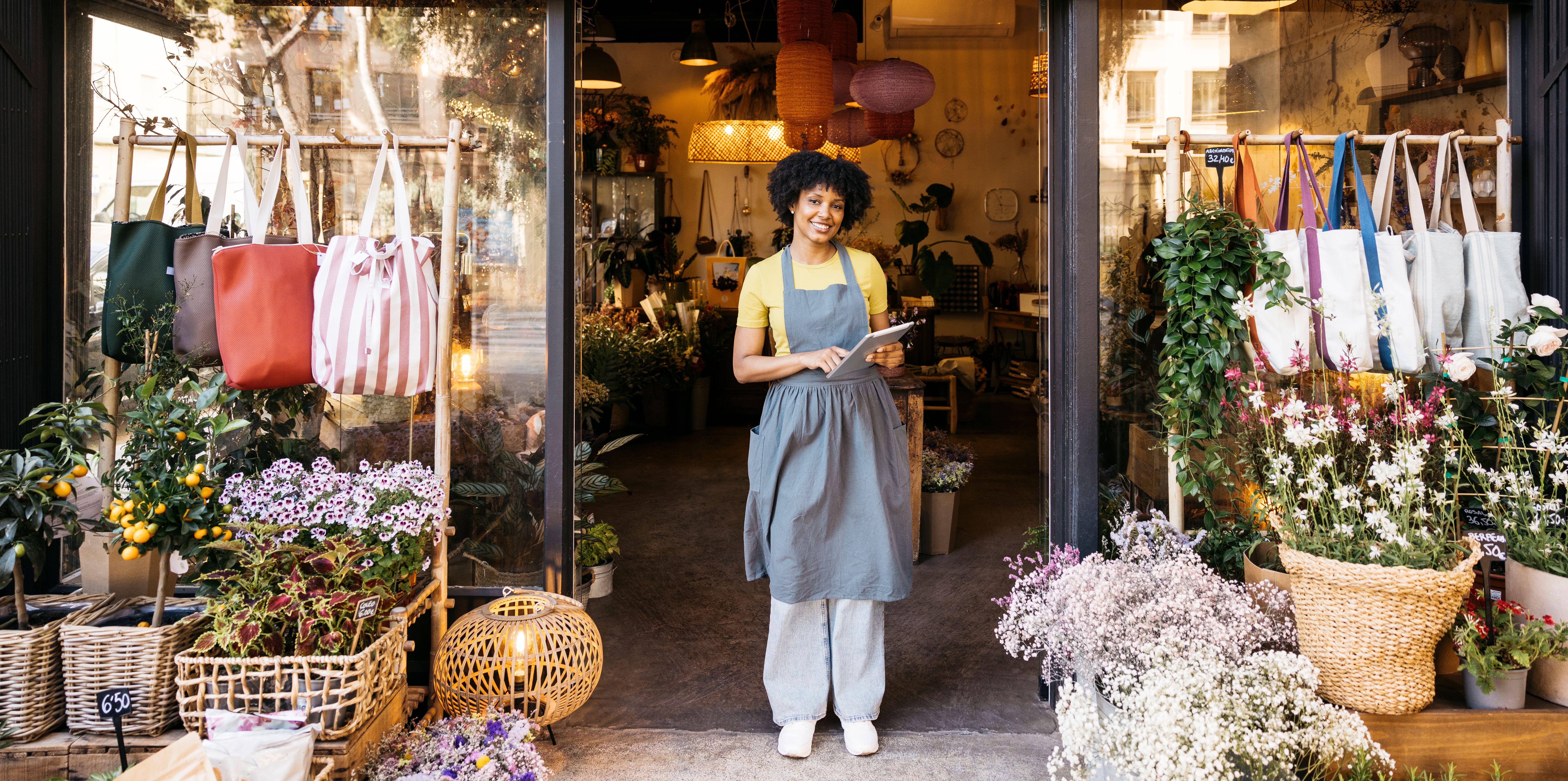 Florist owner smiling and using digital tablet in front of flower shop