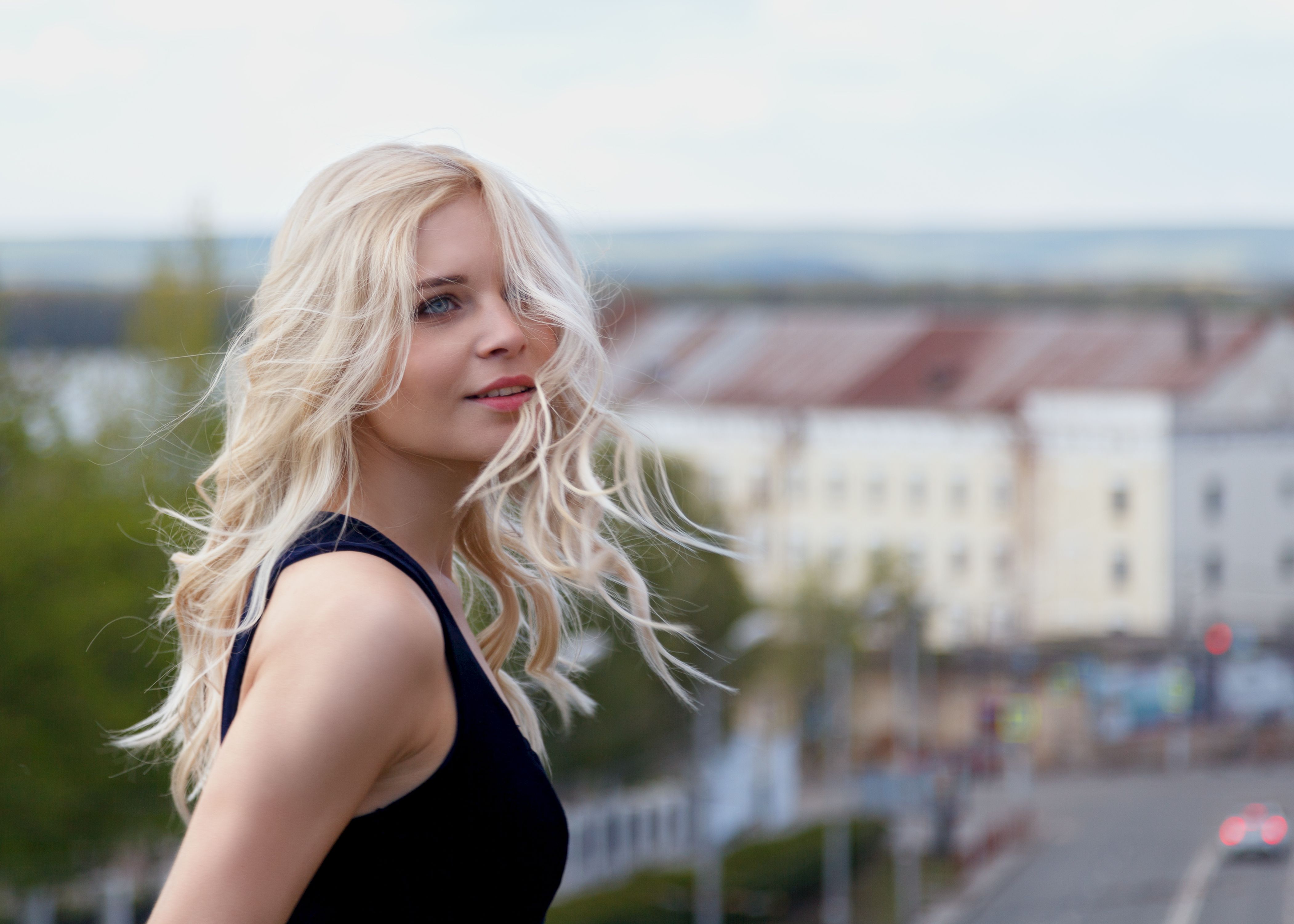 Gorgeous young model woman with wavy blonde hair, looking forward posing in the city. Soft focus Gorgeous young model woman with wavy blonde hair, looking forward posing in the city. Soft focus
