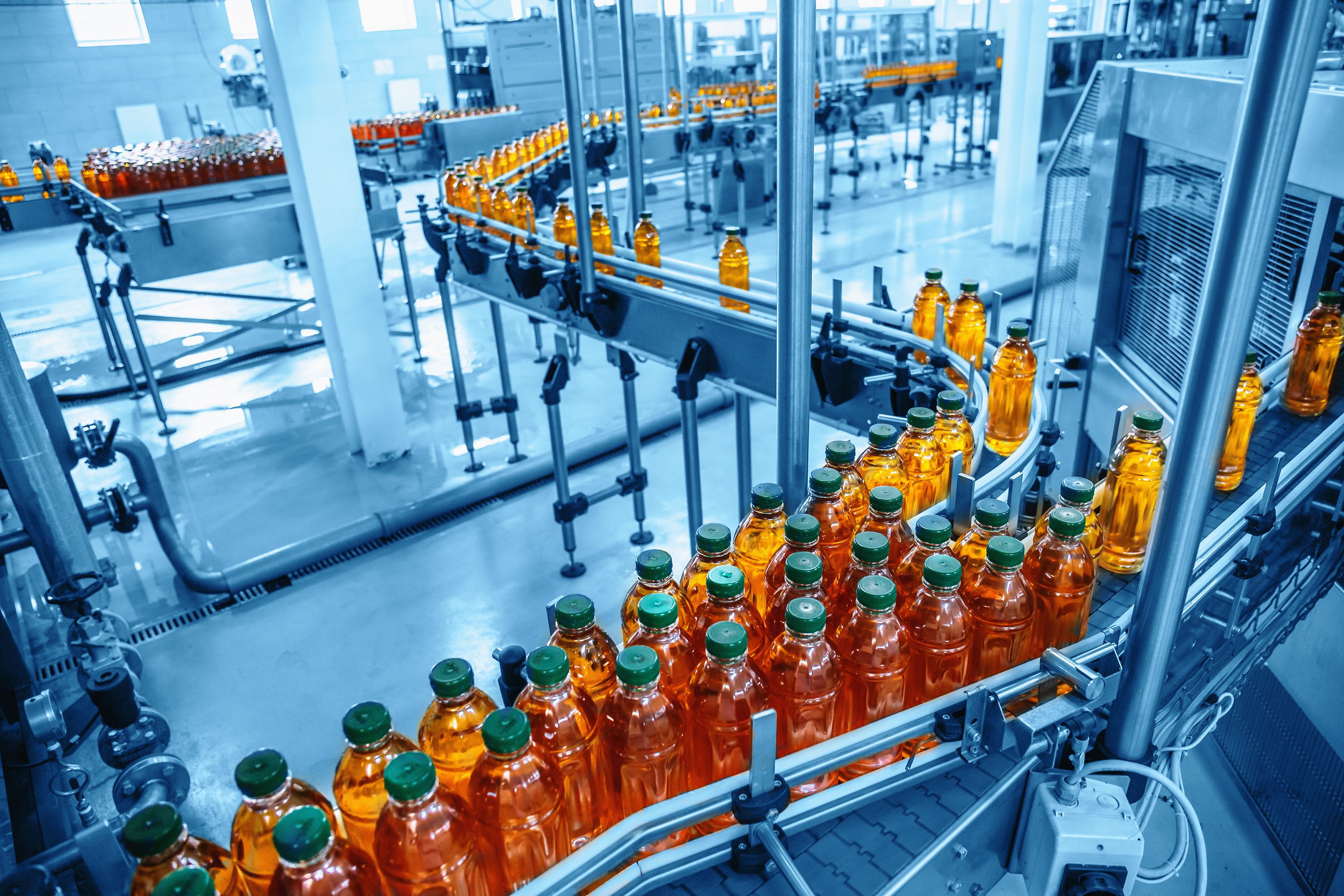 Conveyor belt, juice in bottles on beverage plant or factory interior in blue color, industrial production line