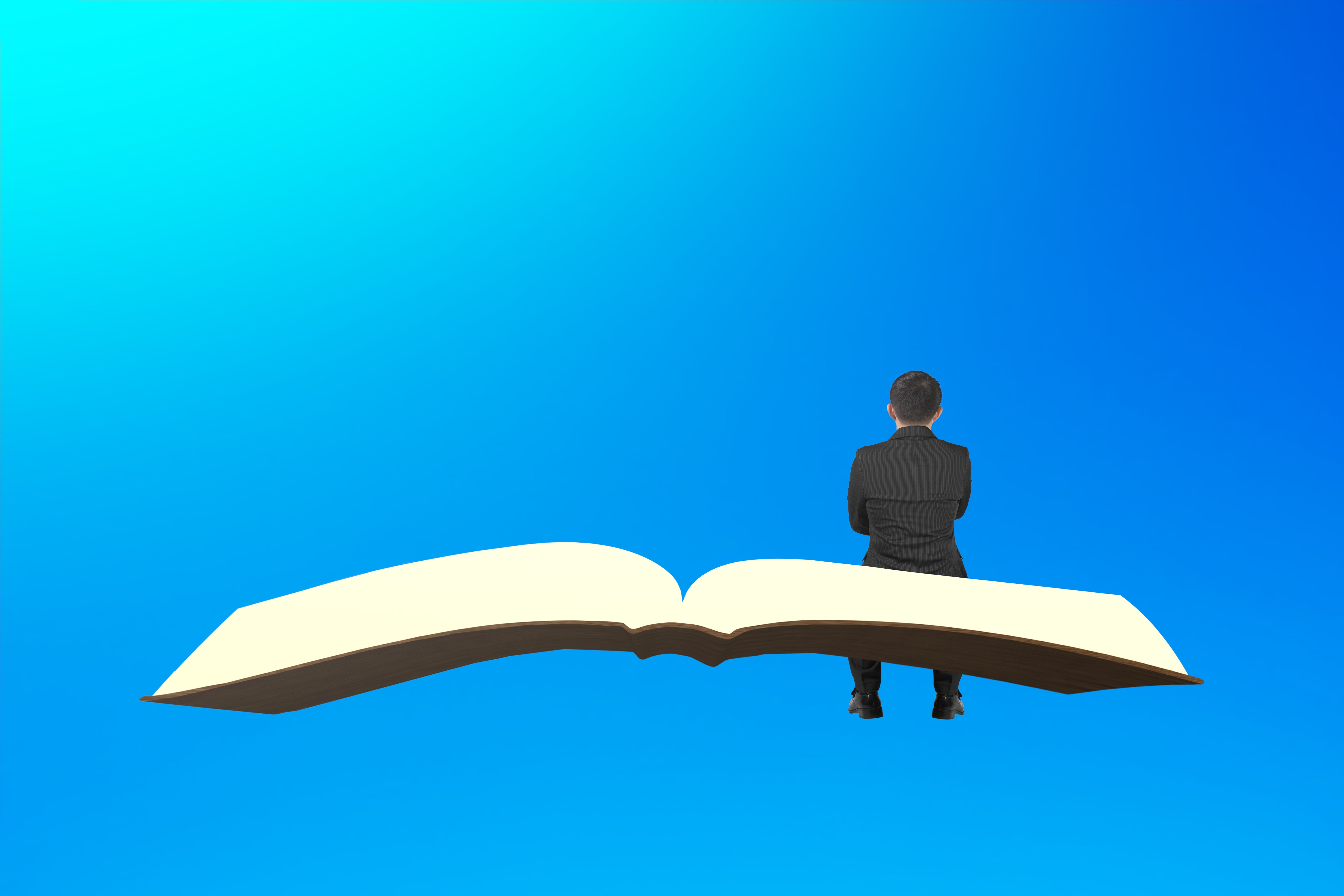 Homem senta-se no livro voando no céu azul