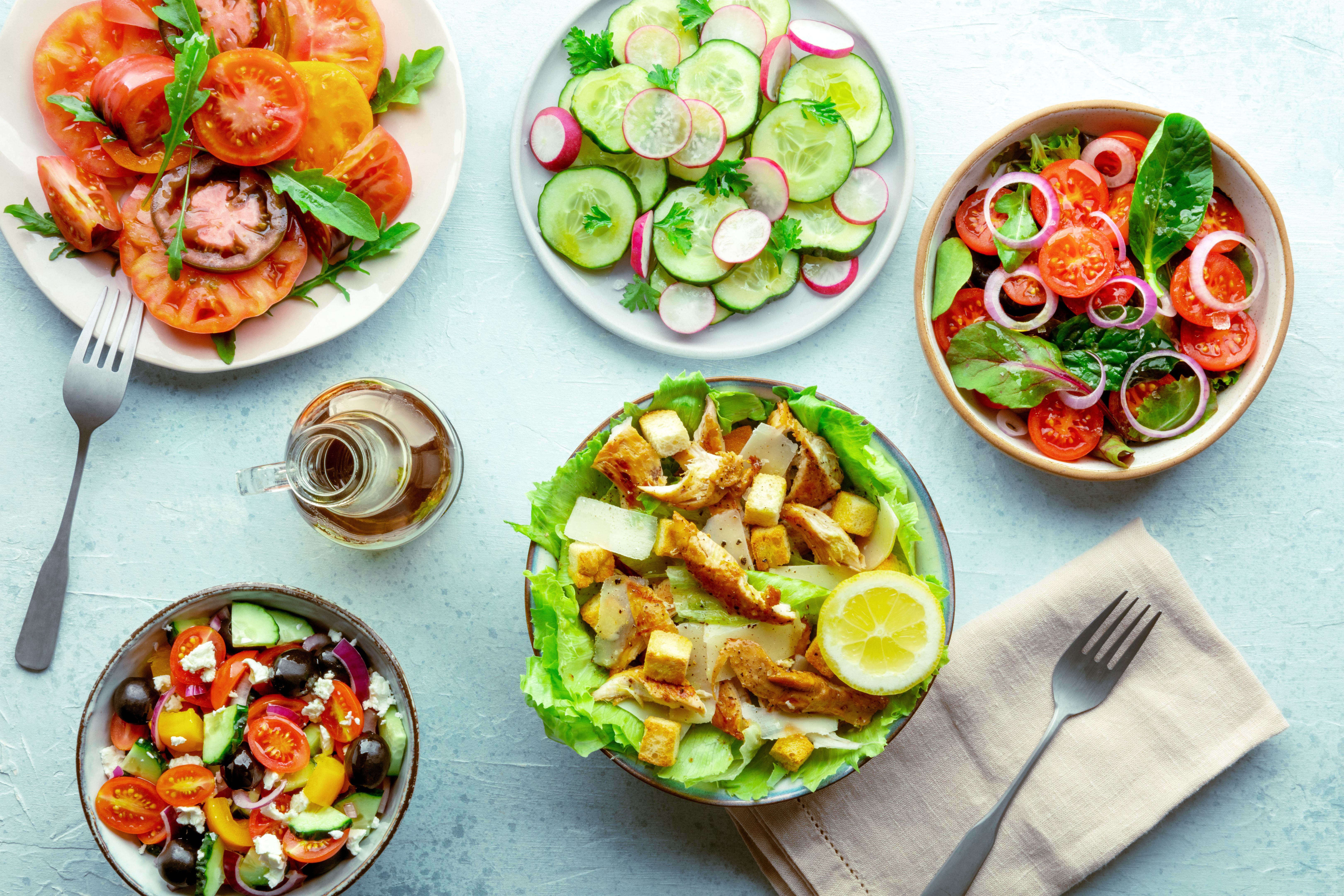 Fresh salads, overhead flat lay shot of an assortment. Variety of plates