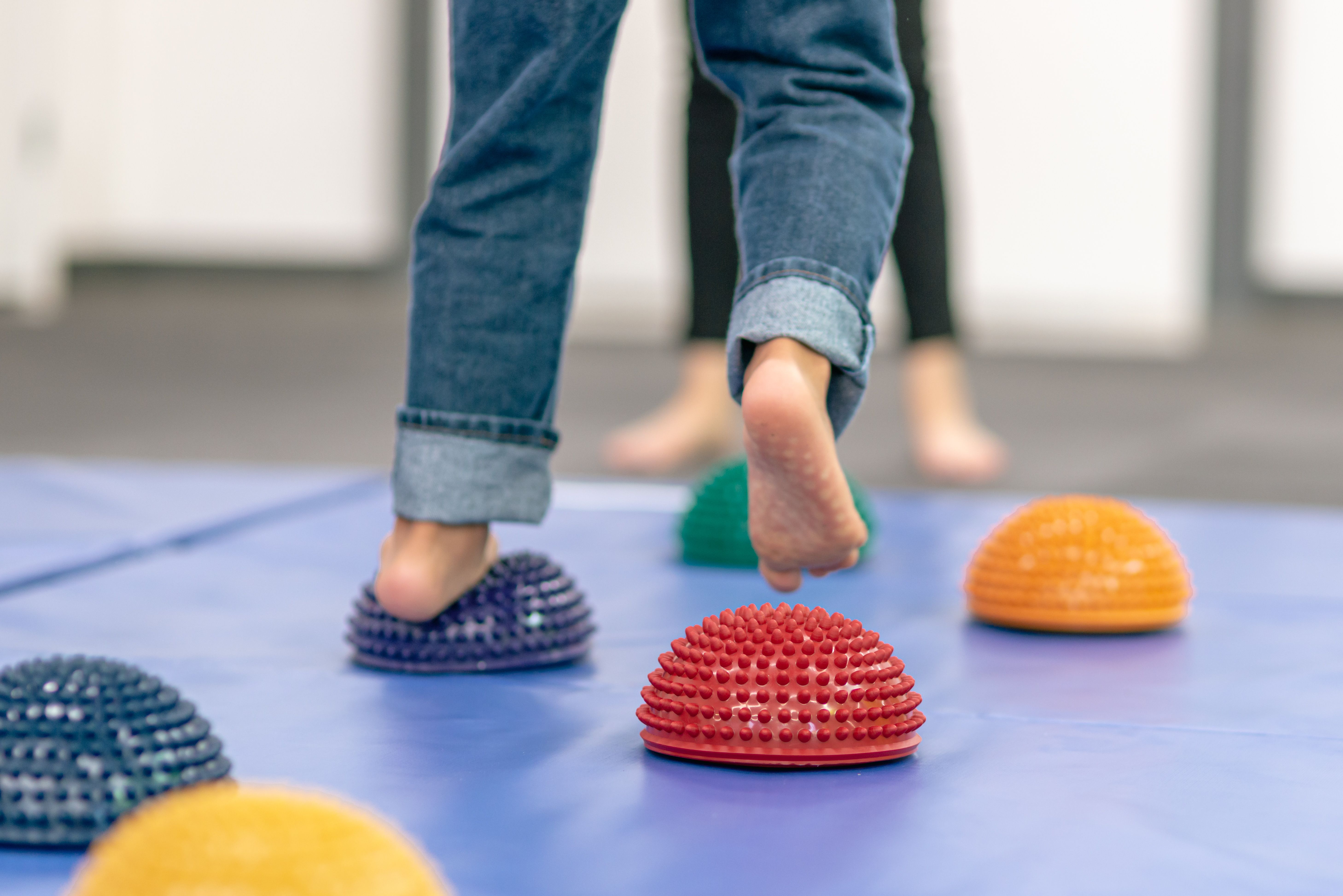 Close up image of feet walking across soft spiky balls in a physical therapy office