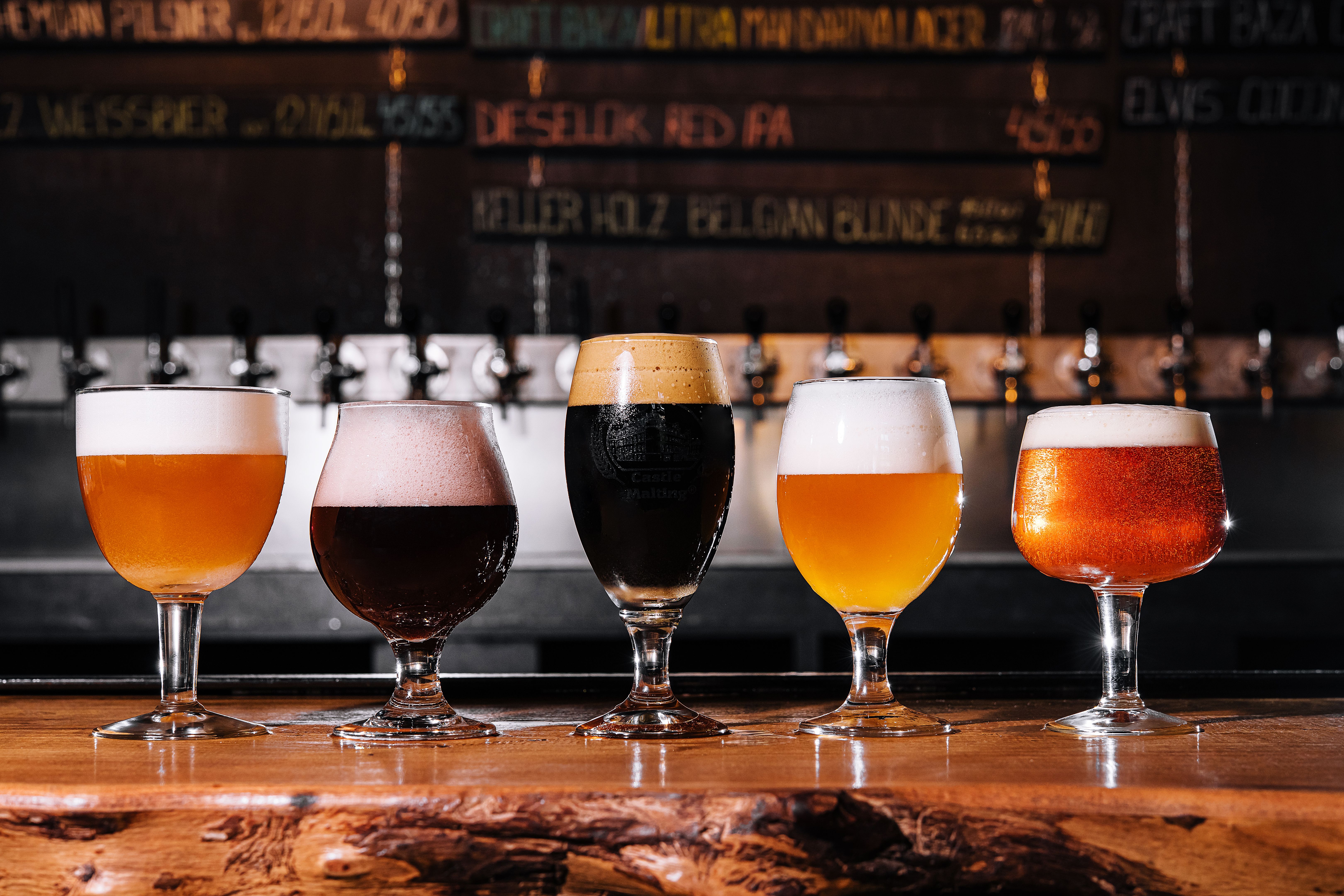 different types of craft beer in glasses on table in pub interior in daylight