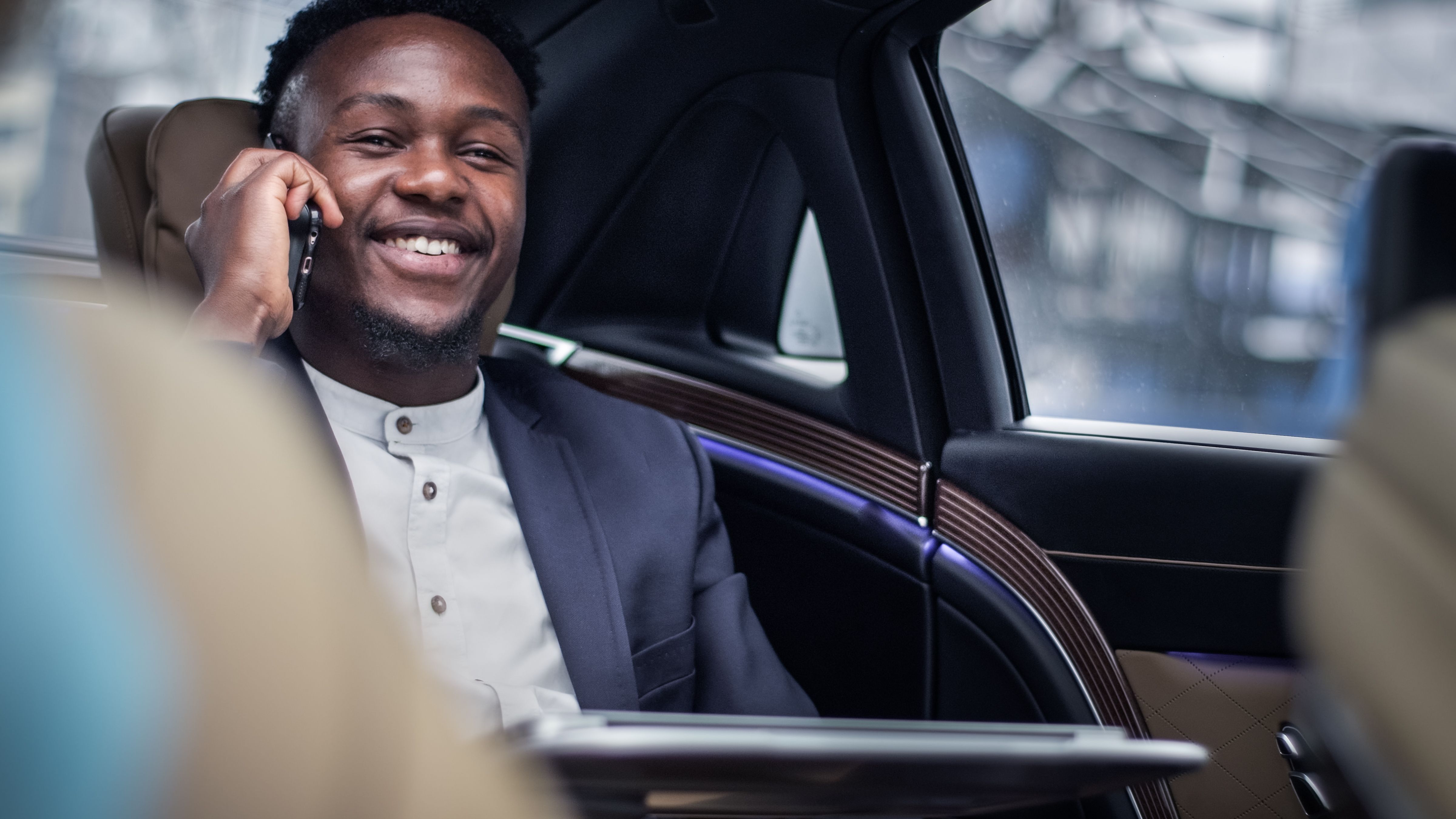 African businessman in taxi, working on the back seat. Making business call