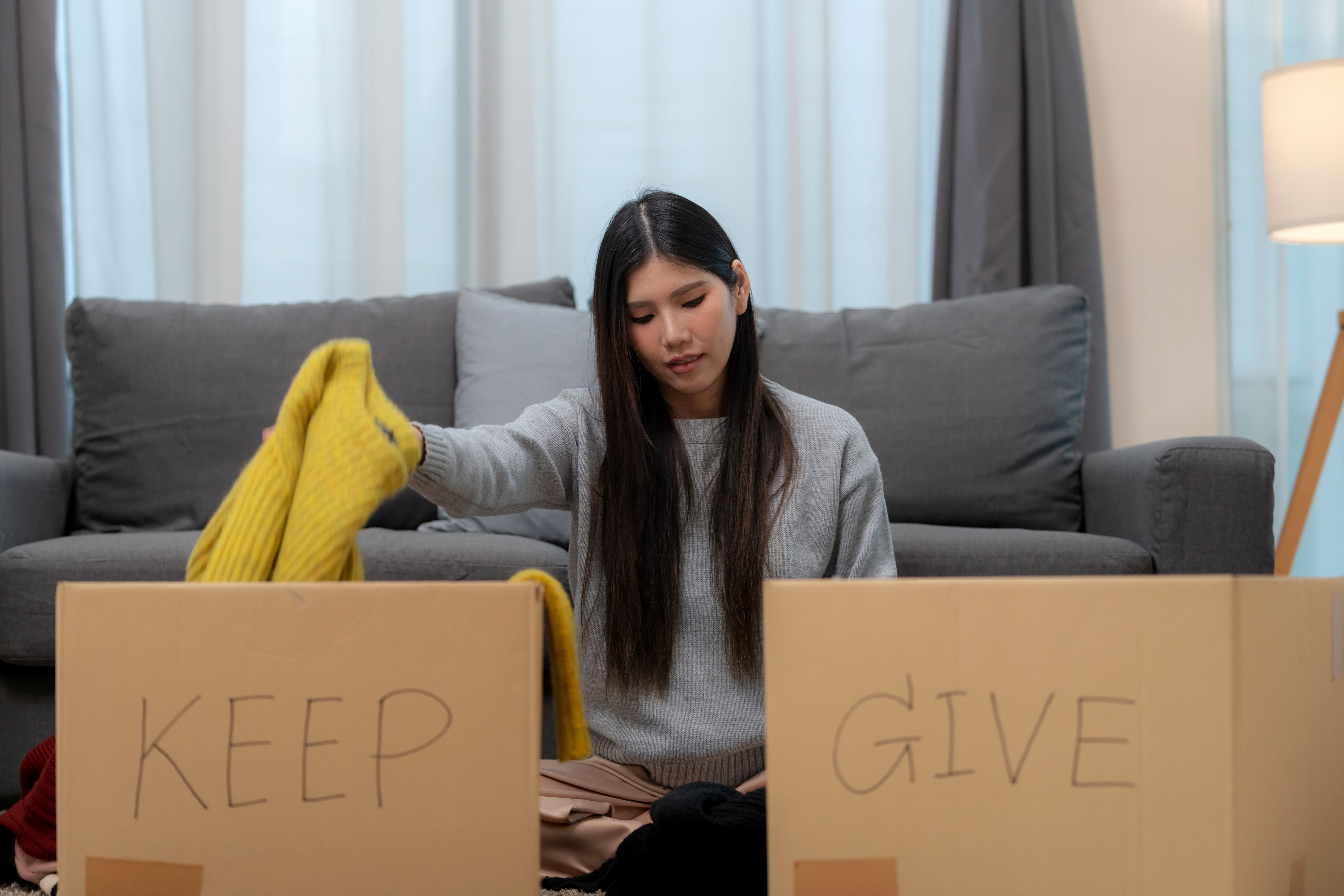 A woman engaging in charity and relief work, sorting and packing clothing for donation. A meaningful moment of giving back to the community, supporting social issues, and promoting sustainability through recycling and donating in her living room. A woman engaging in charity and relief work, sorting and packing clothing for donation. A meaningful moment of giving back to the community, supporting social issues, and promoting sustainability through recycling and donating in her living room.