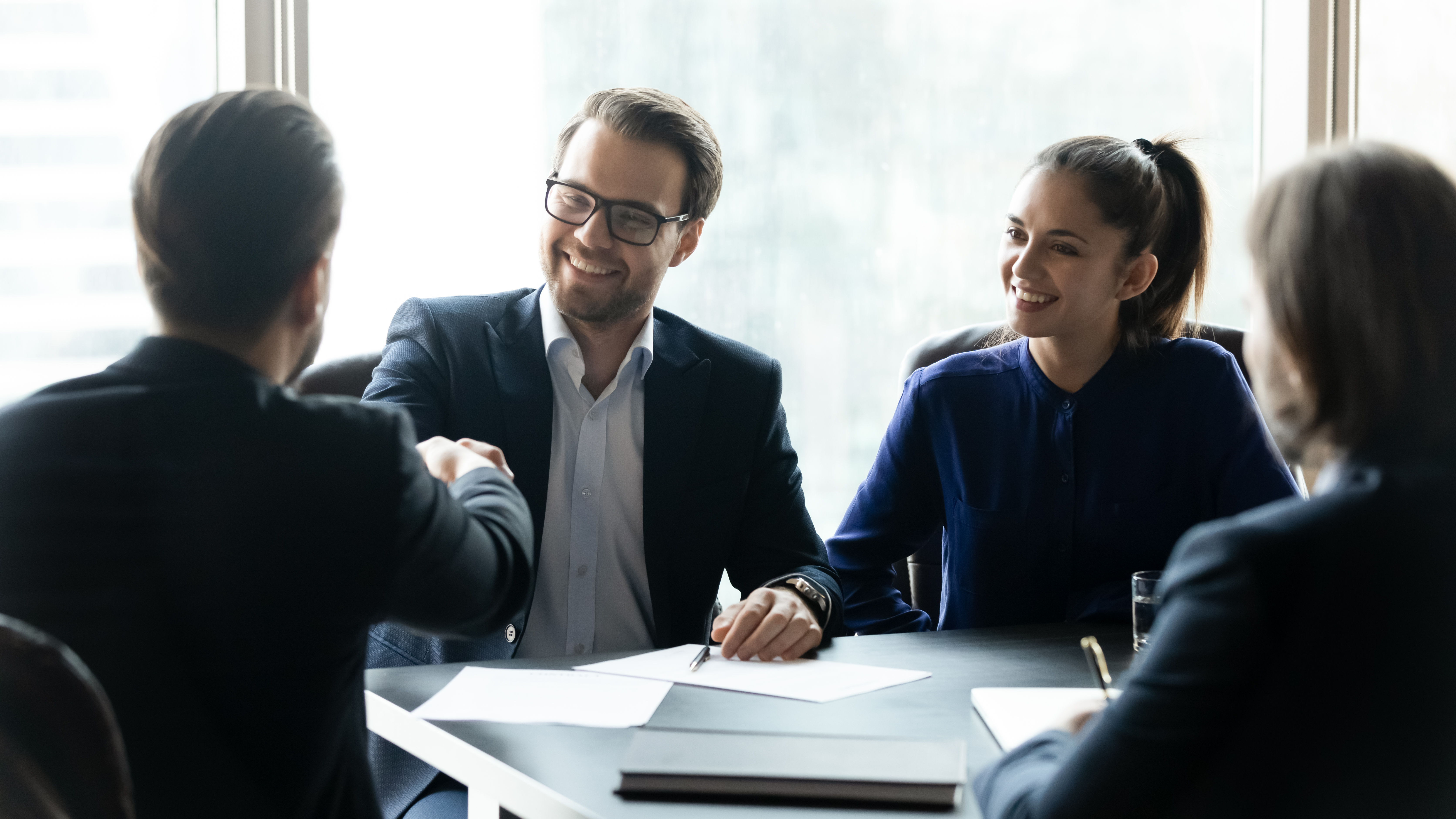 Smiling businesspeople shake hands at team briefing
