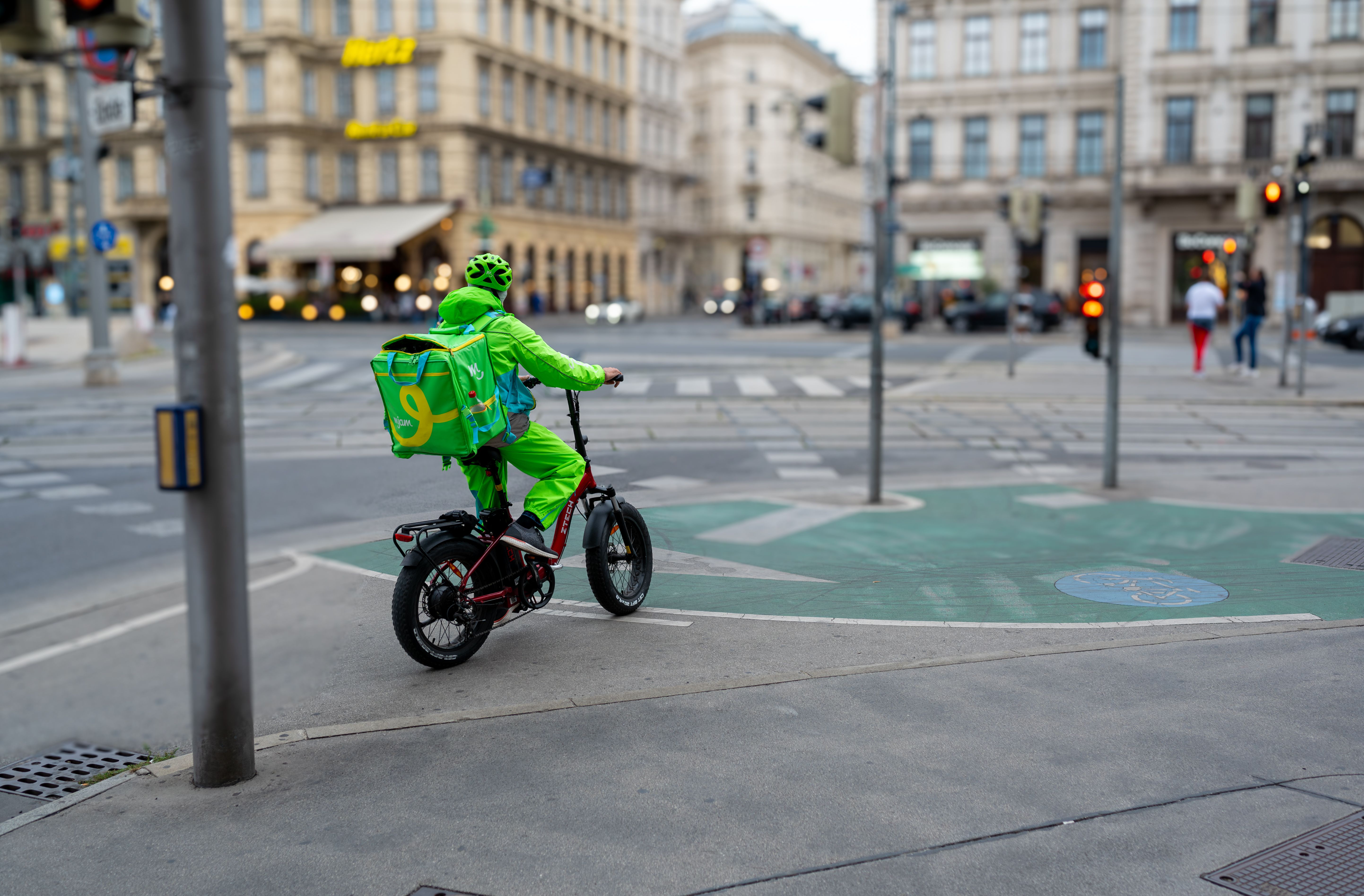 Vienne, Autriche, 21 août 2022. Photo de jour d’un employé de l’entreprise de livraison mjam. Sur son vélo électrique, il attend le feu vert pour entrer dans la circulation. La ville s’est estompée en arrière-plan. Vienne, Autriche, 21 août 2022. Photo de jour d’un employé de l’entreprise de livraison mjam. Sur son vélo électrique, il attend le feu vert pour entrer dans la circulation. La ville s’est estompée en arrière-plan.