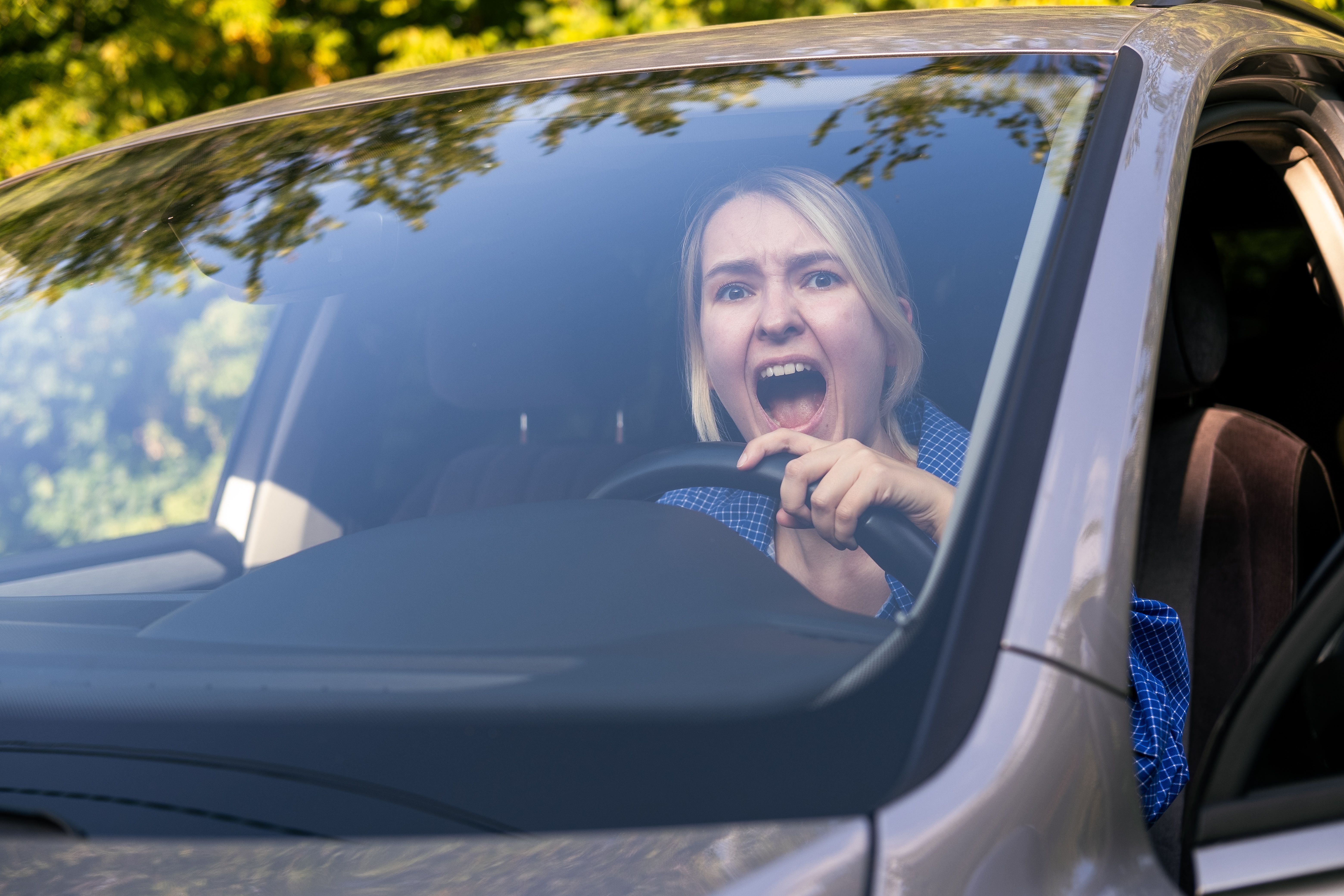 Stressed woman drive car feeling sad and shocked. Caucasian blond girl shouting and feeling frustrated.
