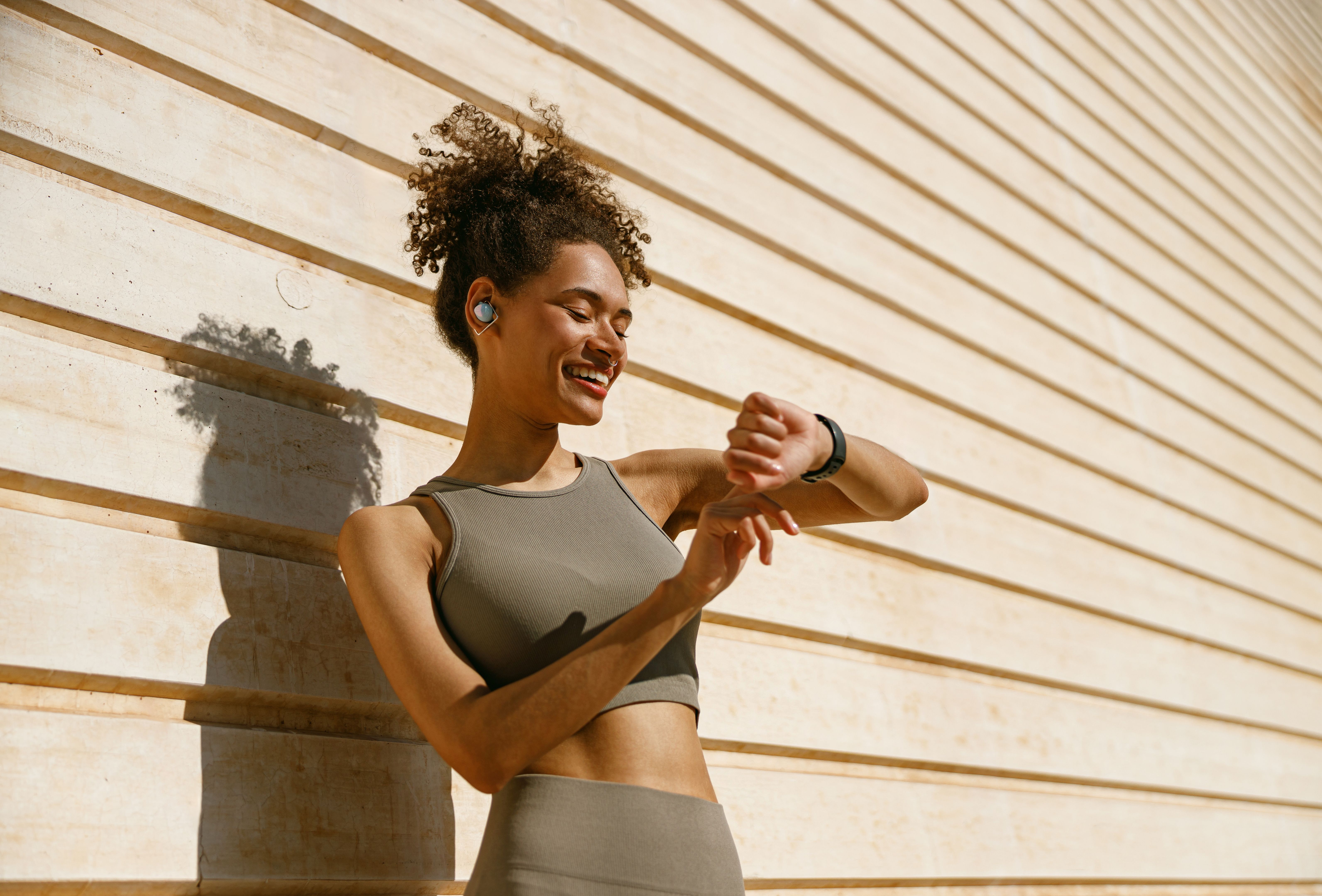 Young woman in sportswear looking on smartwatch before exercising. Outdoor sports in the morning