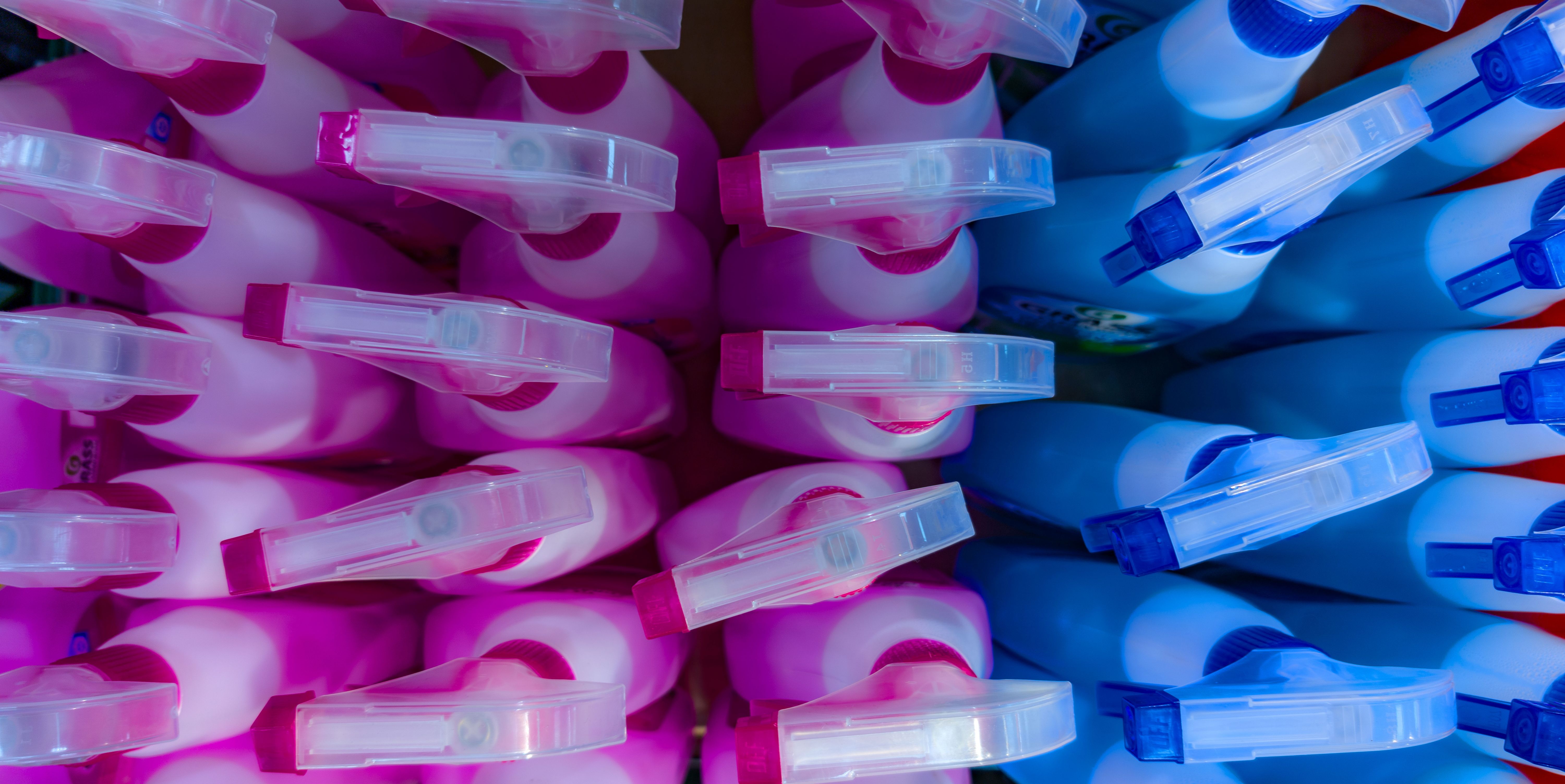 Colorful display of cleaning products arranged in a store, showcasing pink and blue bottles in neat rows during daytime shopping hours Colorful display of cleaning products arranged in a store, showcasing pink and blue bottles in neat rows during daytime shopping hours