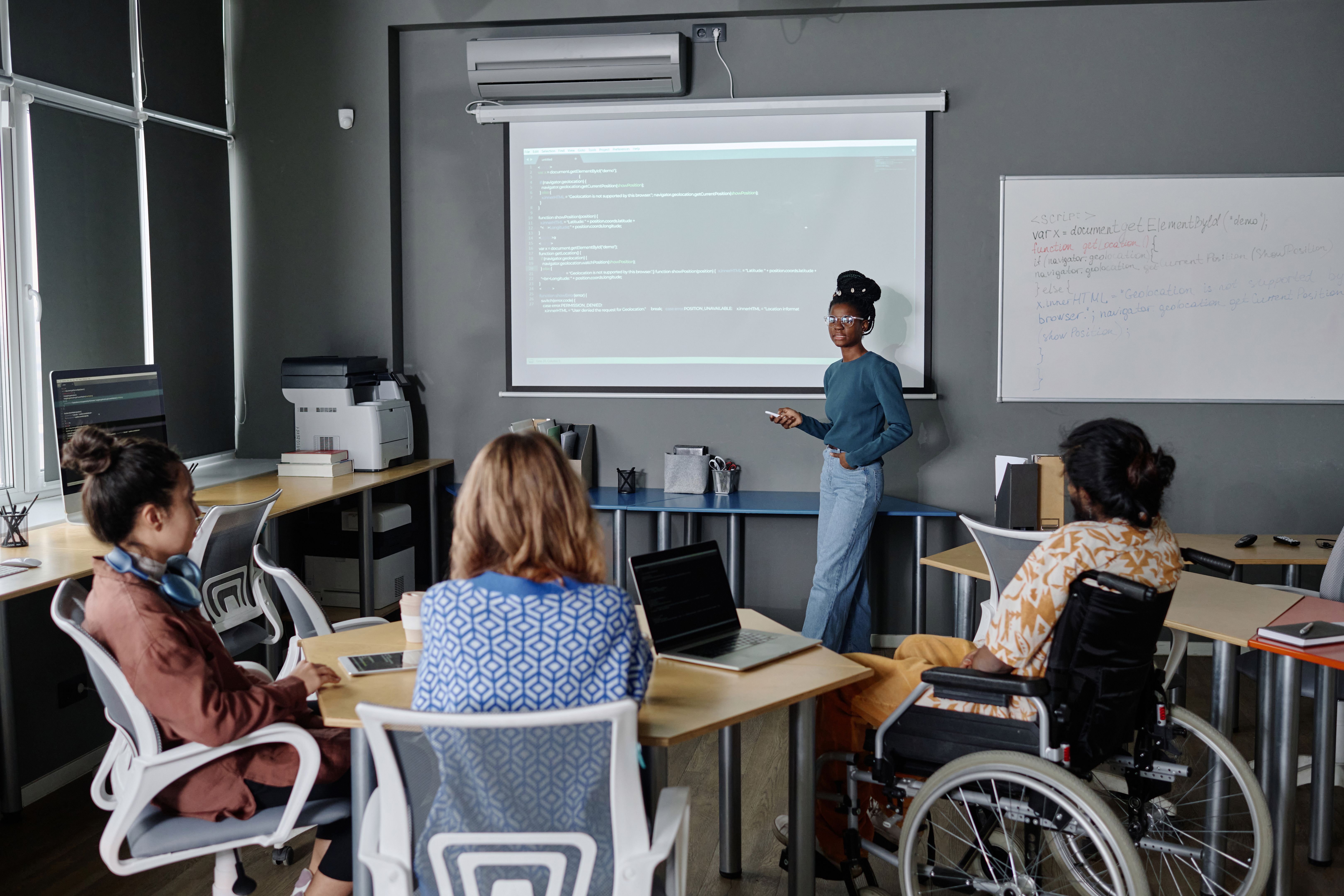 Black Female IT Worker Showing Codes on Digital Board to Her Coworkers Black Female IT Worker Showing Codes on Digital Board to Her Coworkers