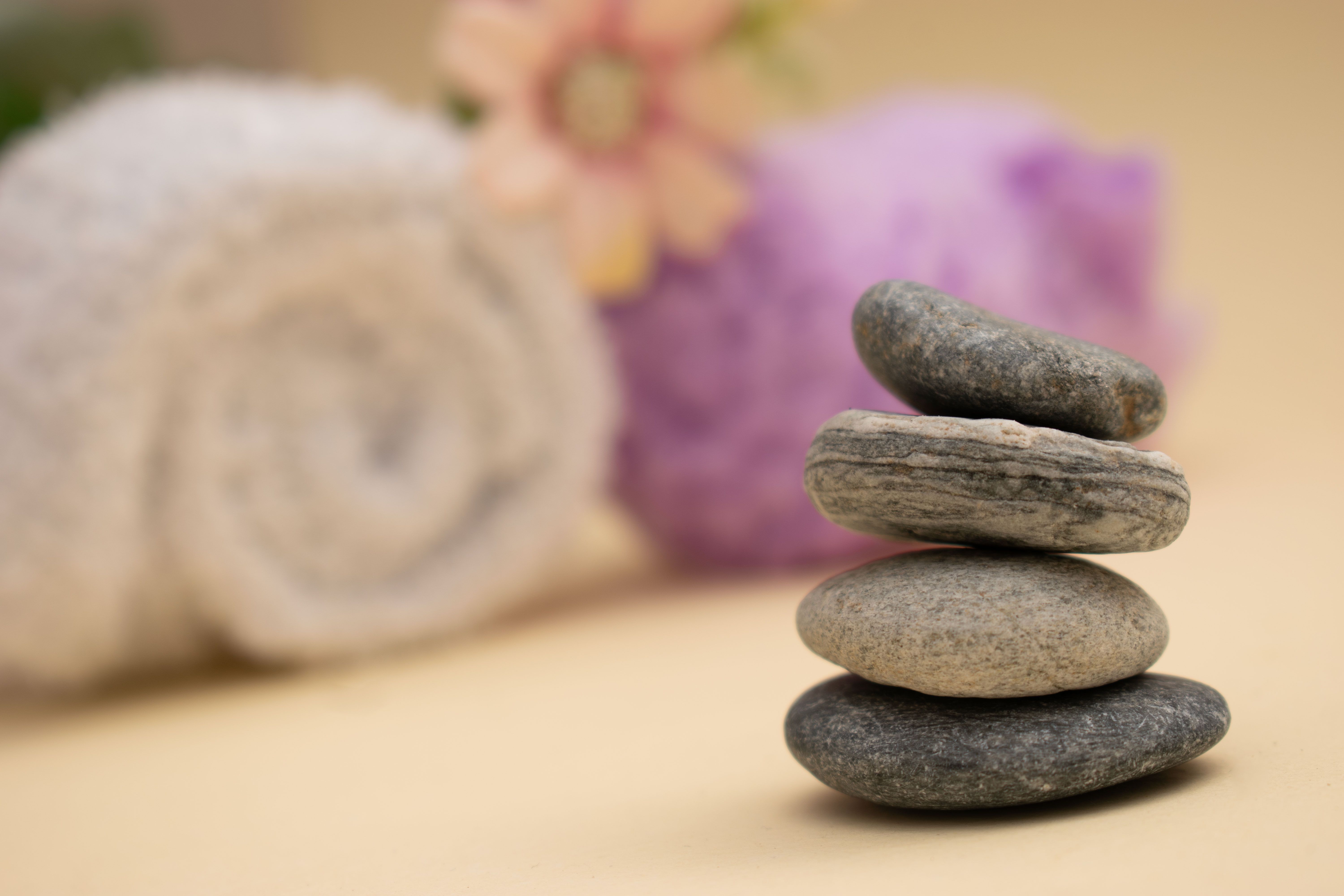 Stack of zen stones with spa towels and flowers in the background