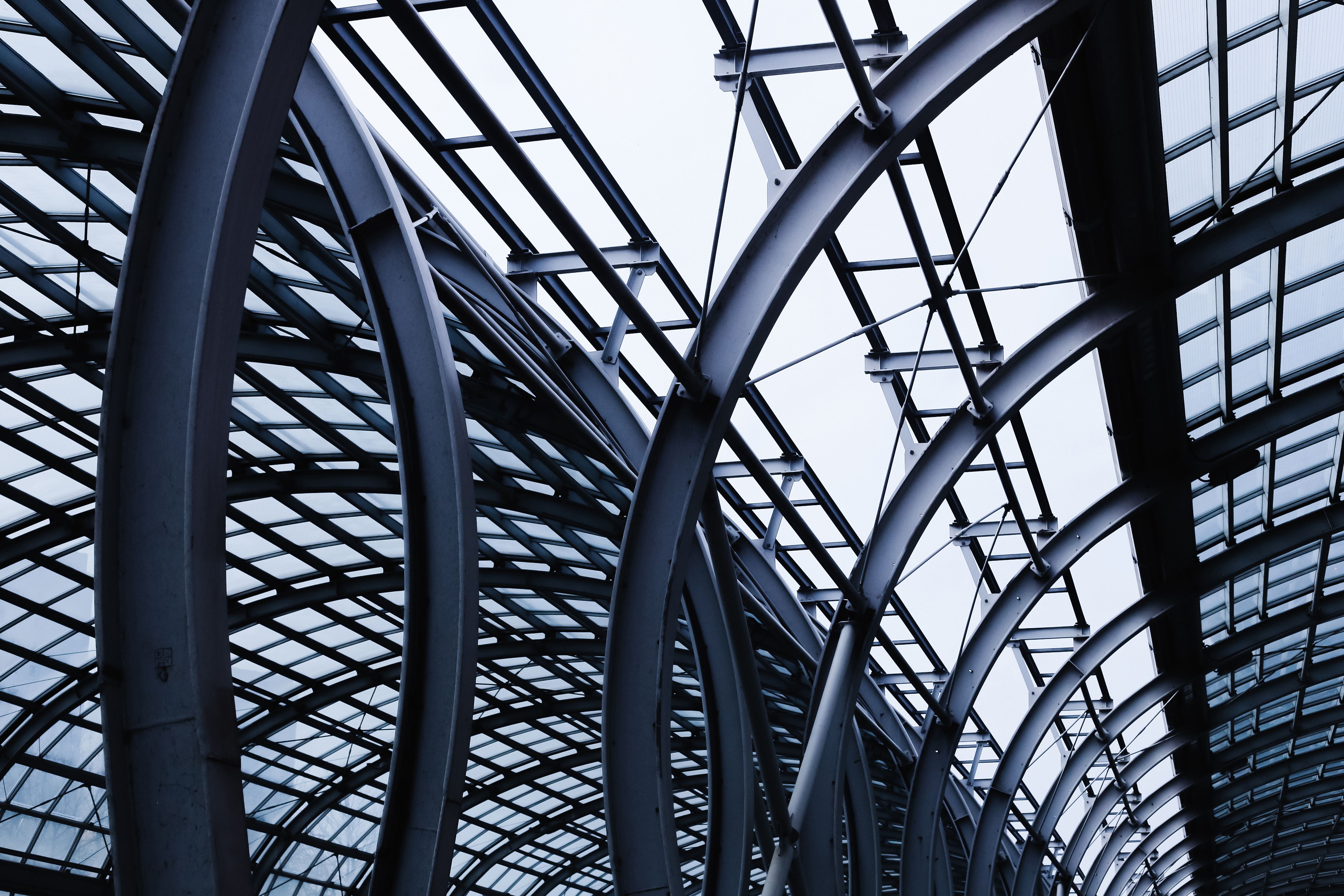 Modern curved glass architecture of train station roof. Steel structure with geometric pattern and transparent panels.