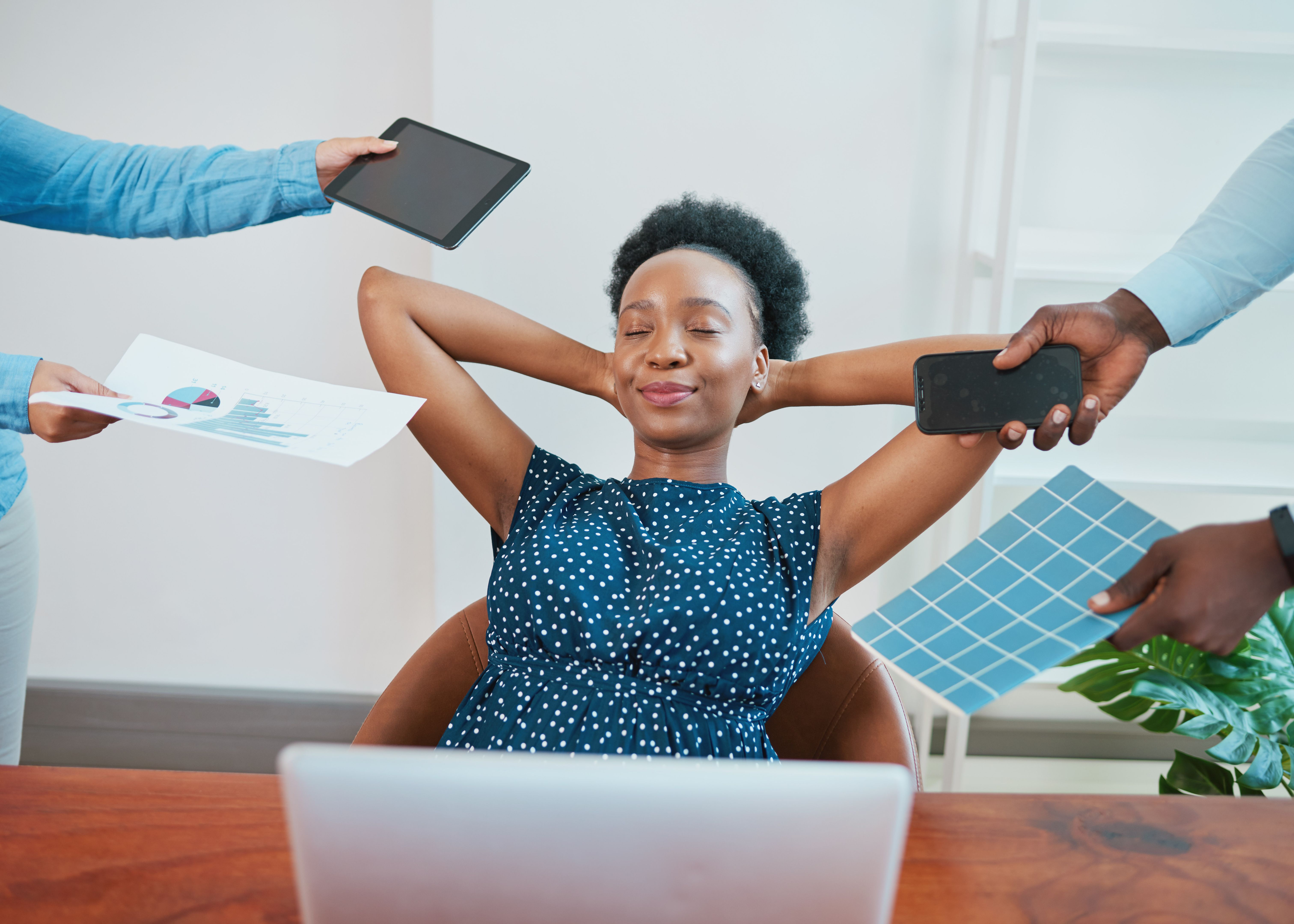 Young Black woman relaxes in her office while coworkers make demands Young Black woman relaxes in her office while coworkers make demands
