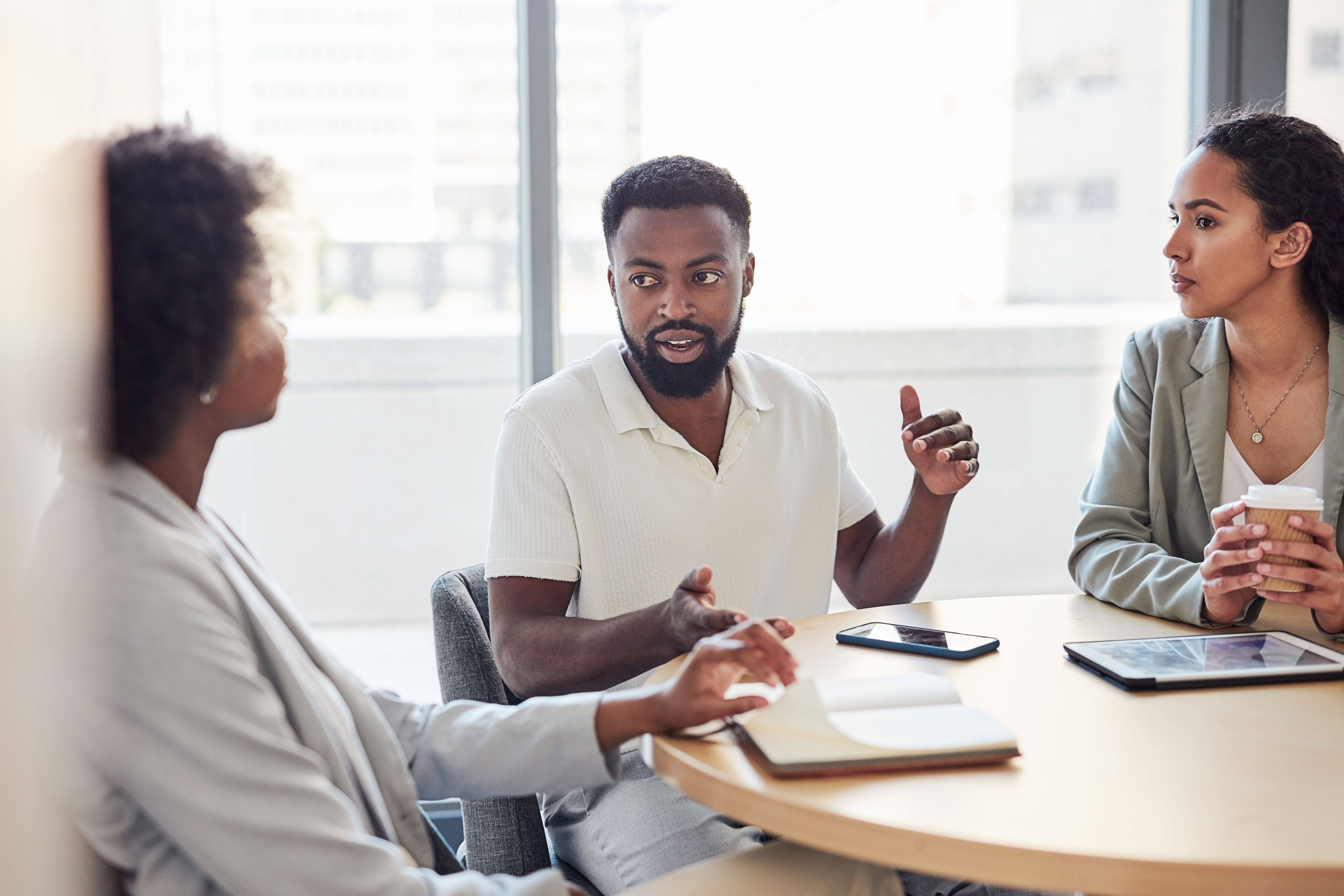 A group of young business people negotiating a business strategy in the boardroom. A young Afro American male manager explains an important point on the upcoming new projects in a board meeting. A group of young business people negotiating a business strategy in the boardroom. A young Afro American male manager explains an important point on the upcoming new projects in a board meeting.