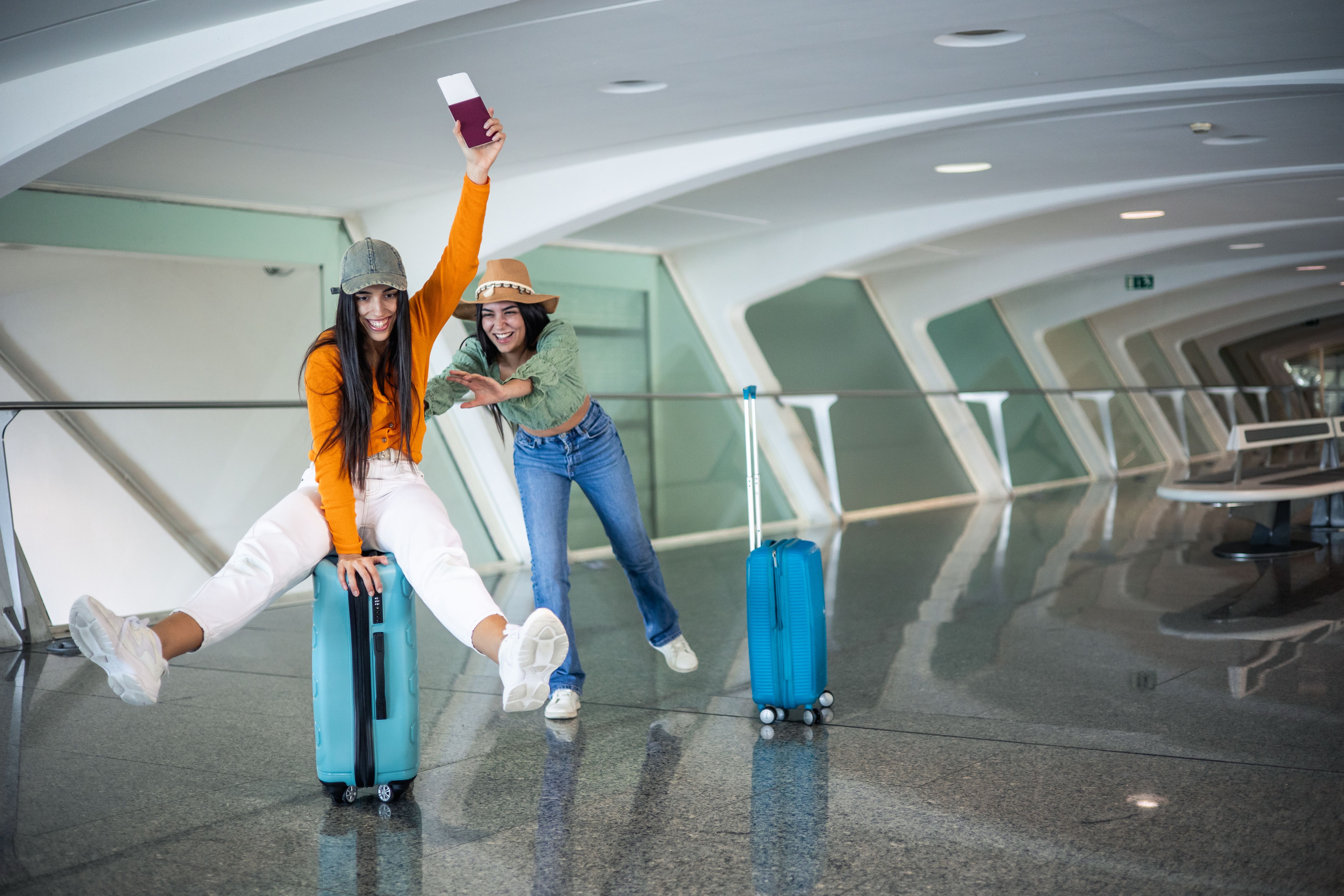 two multicultural friends having fun with luggage at the airport with passport in hand