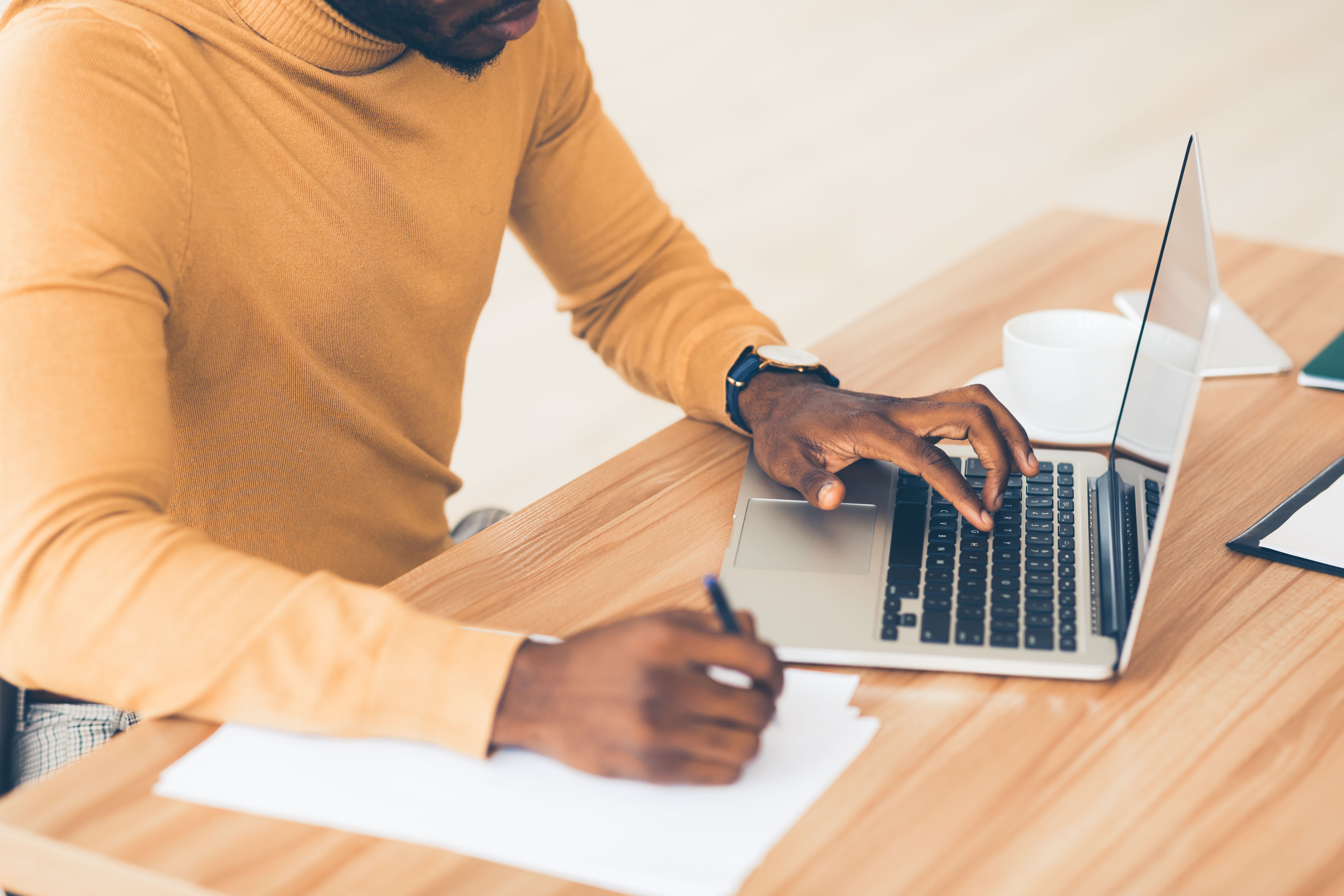 Unrecognizable afro guy working on his laptop and writing content
