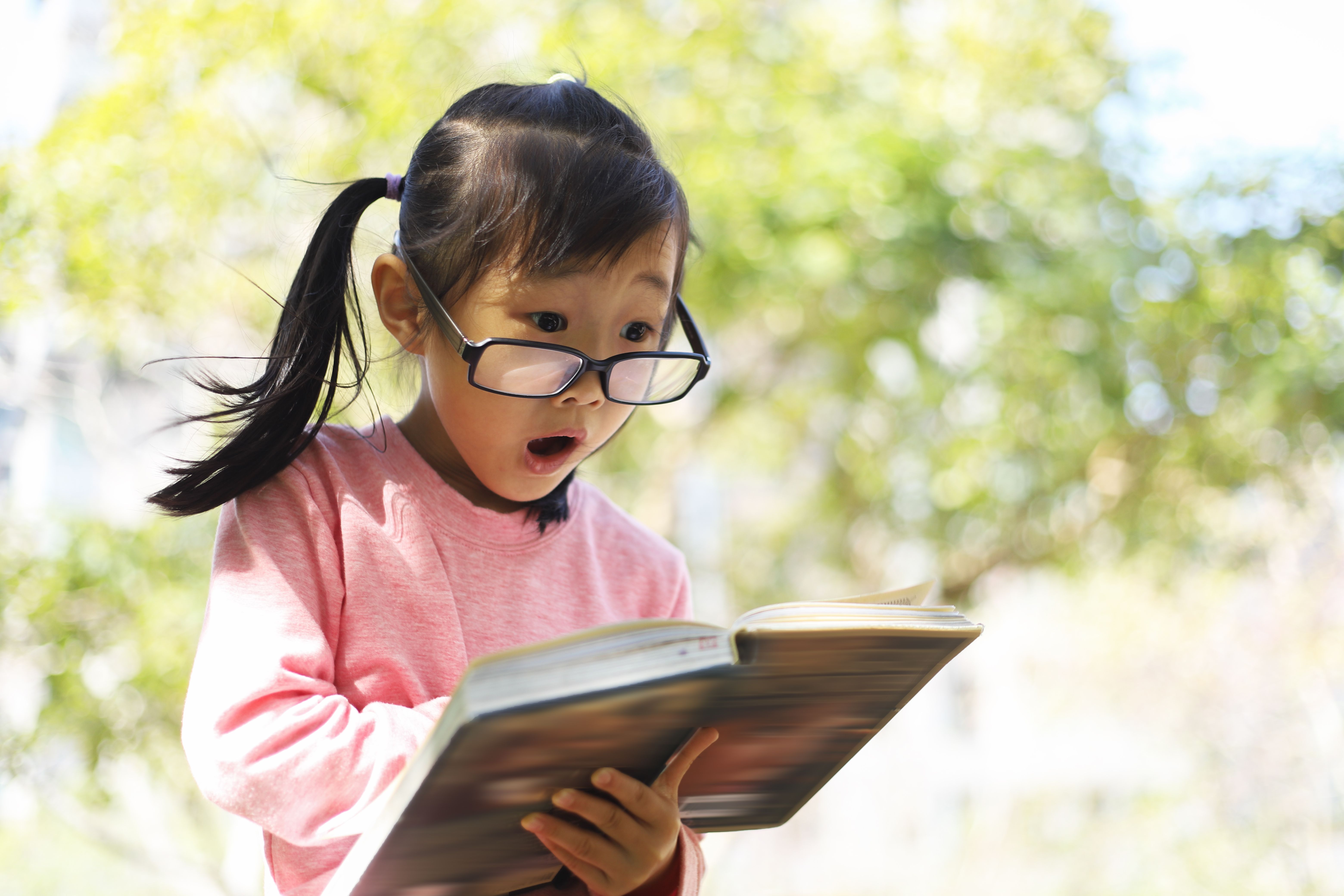 a girl reading a book in a park.