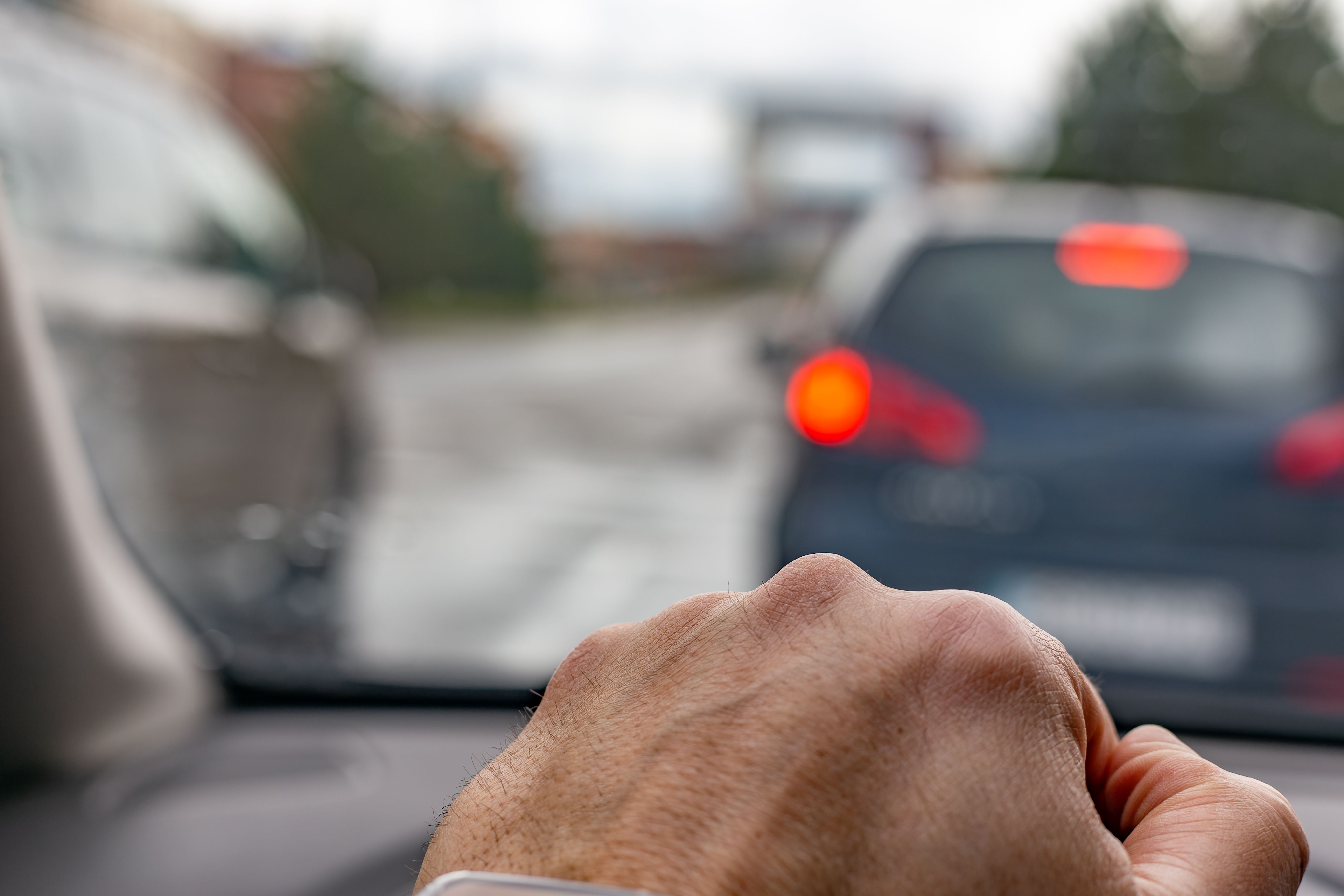 Main d’un homme sur le volant d’une voiture traversant la ville un jour de pluie.