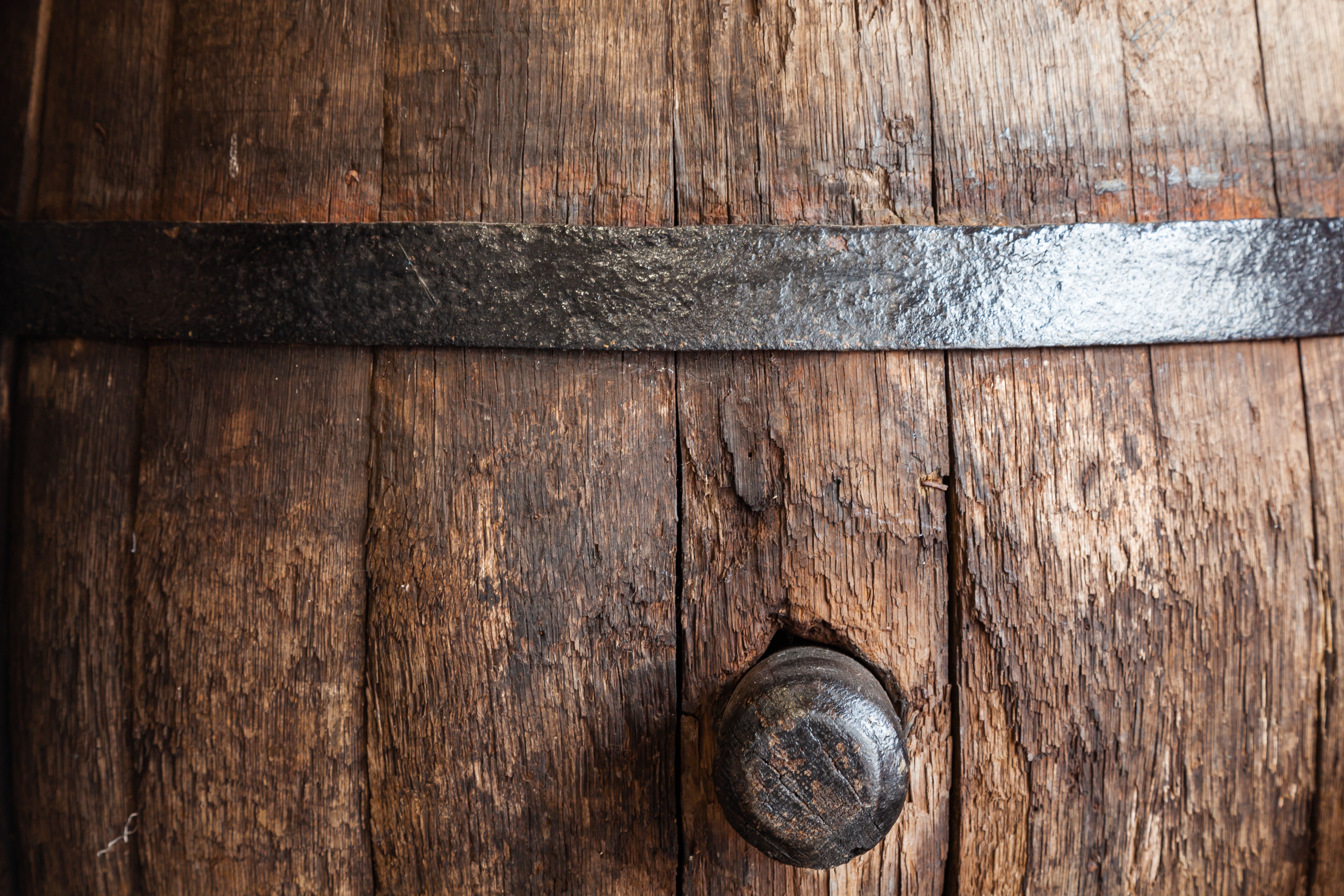Antique wooden oak barrel with a wooden stopper inserted on the side.