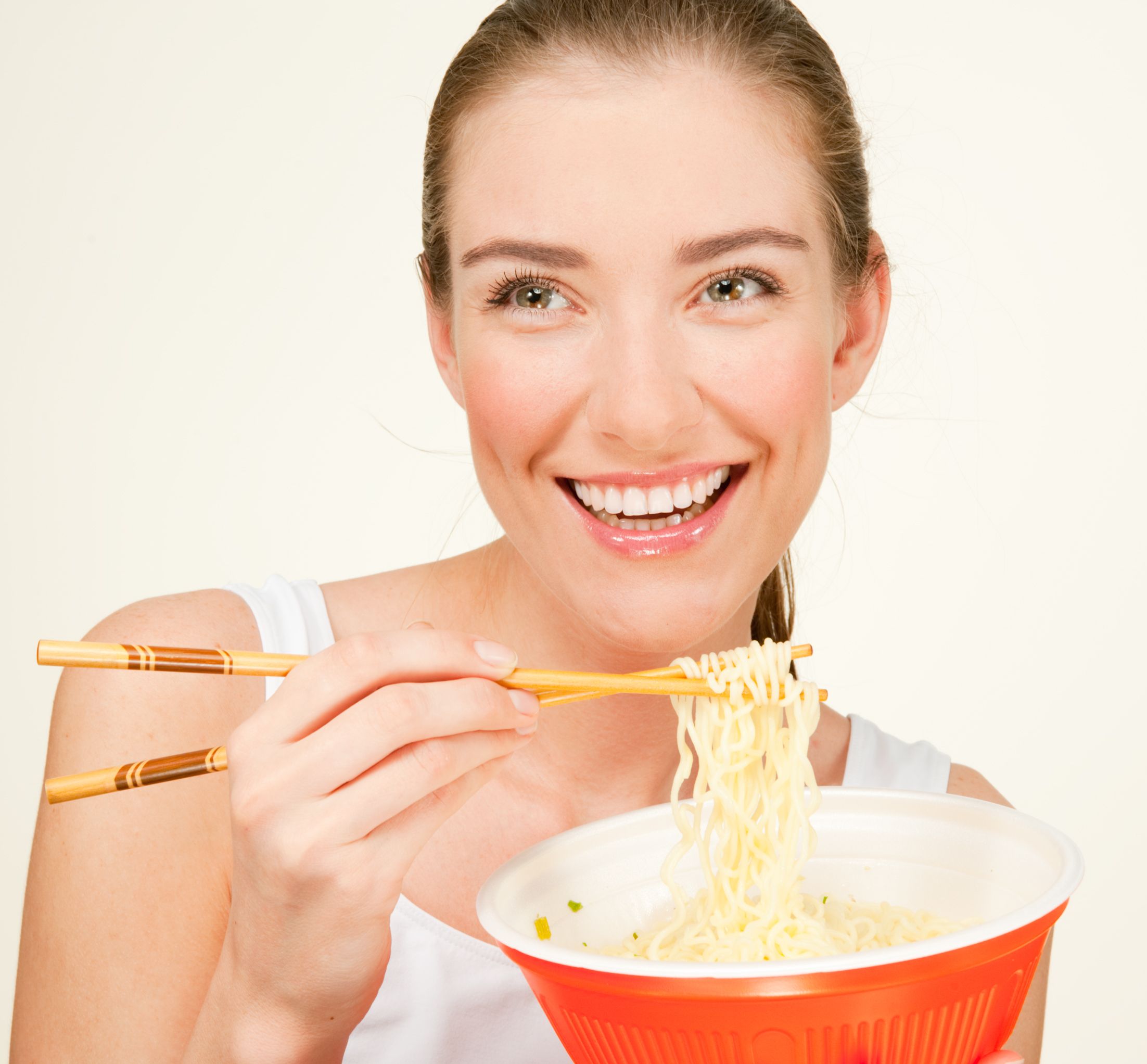 Smiling young woman eats noodles