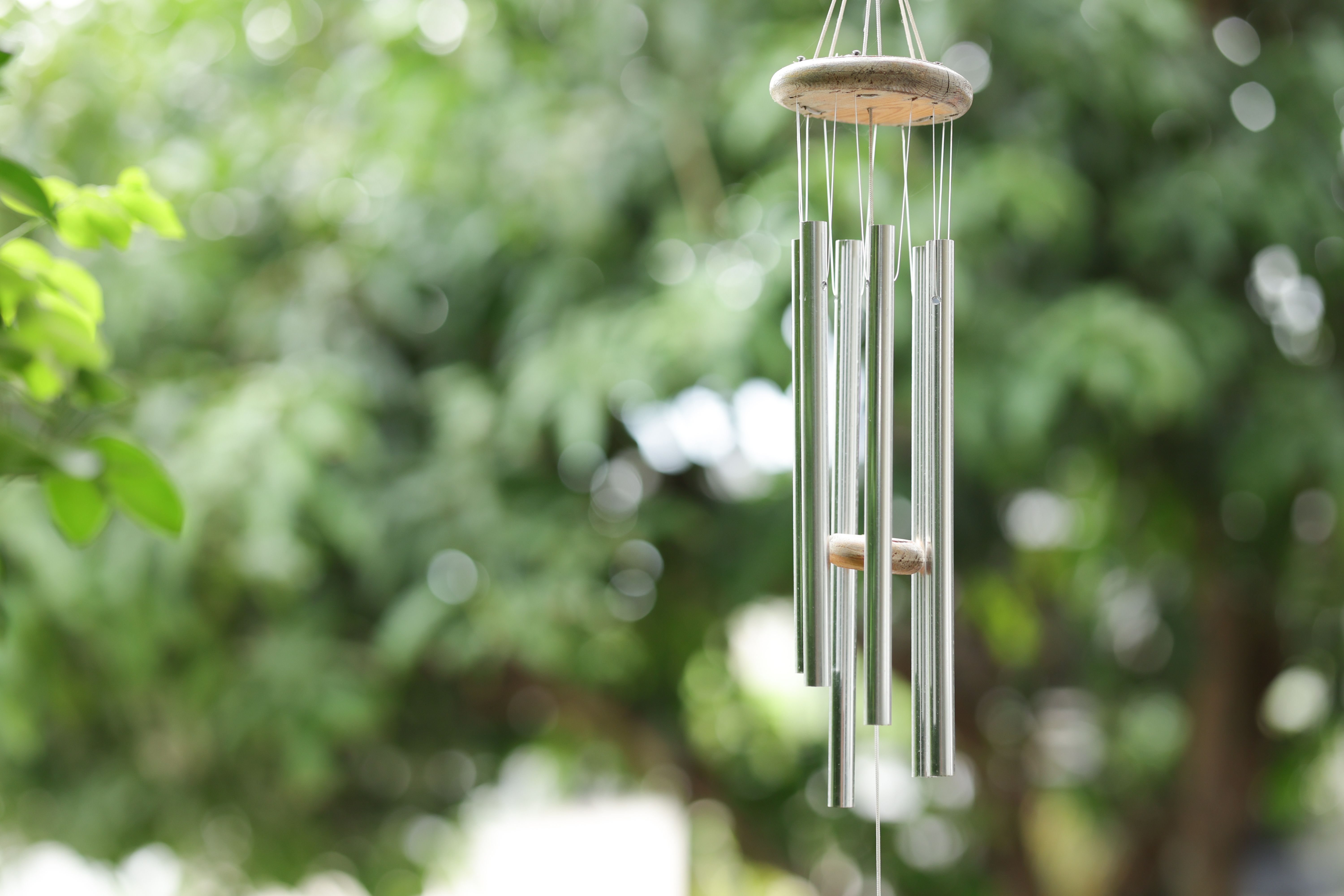 Wind chimes with green blurred background. Metal wind chimes with blurred background.
