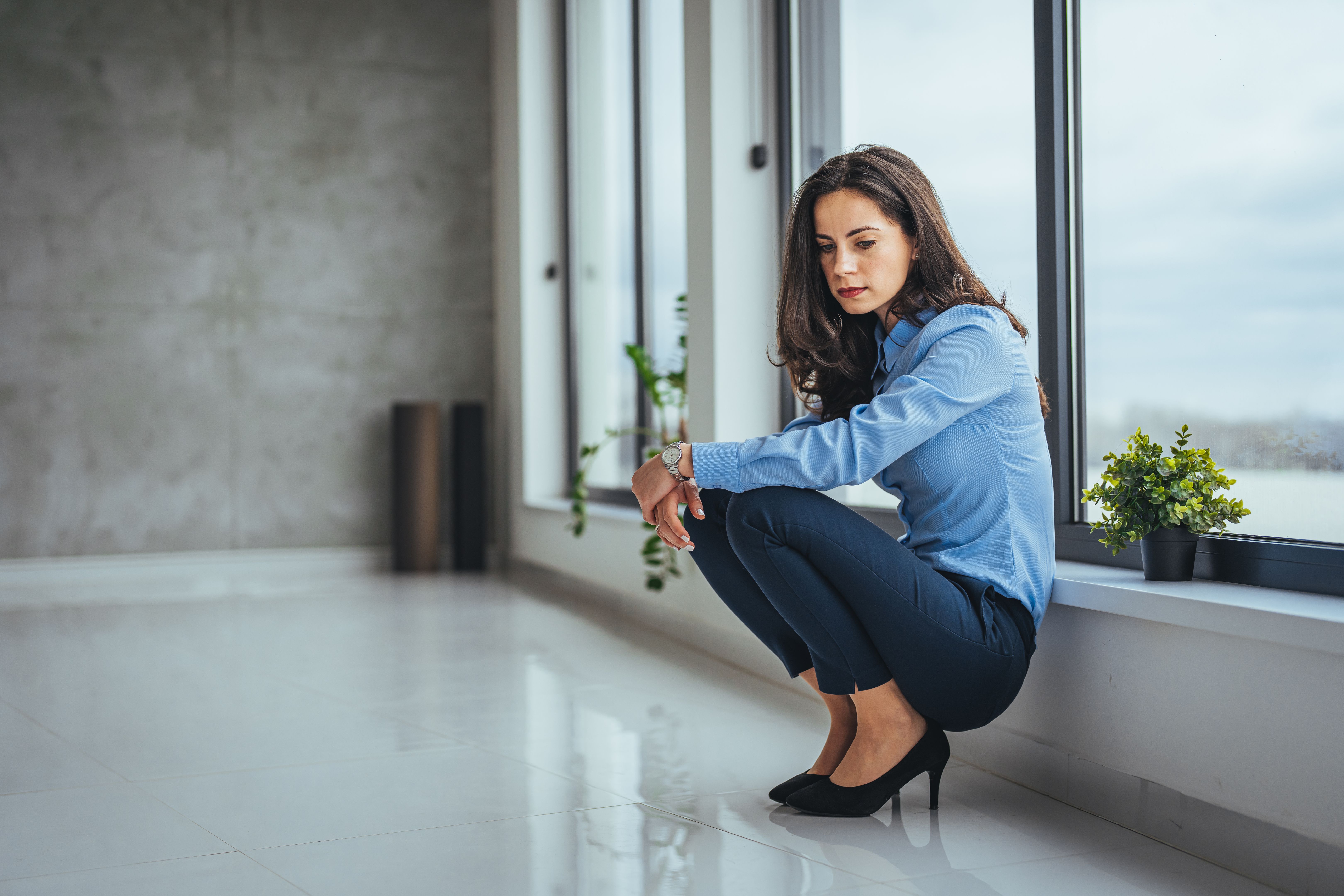 Shot of a stressed businesswoman sitting on the floor outside the boardroom.