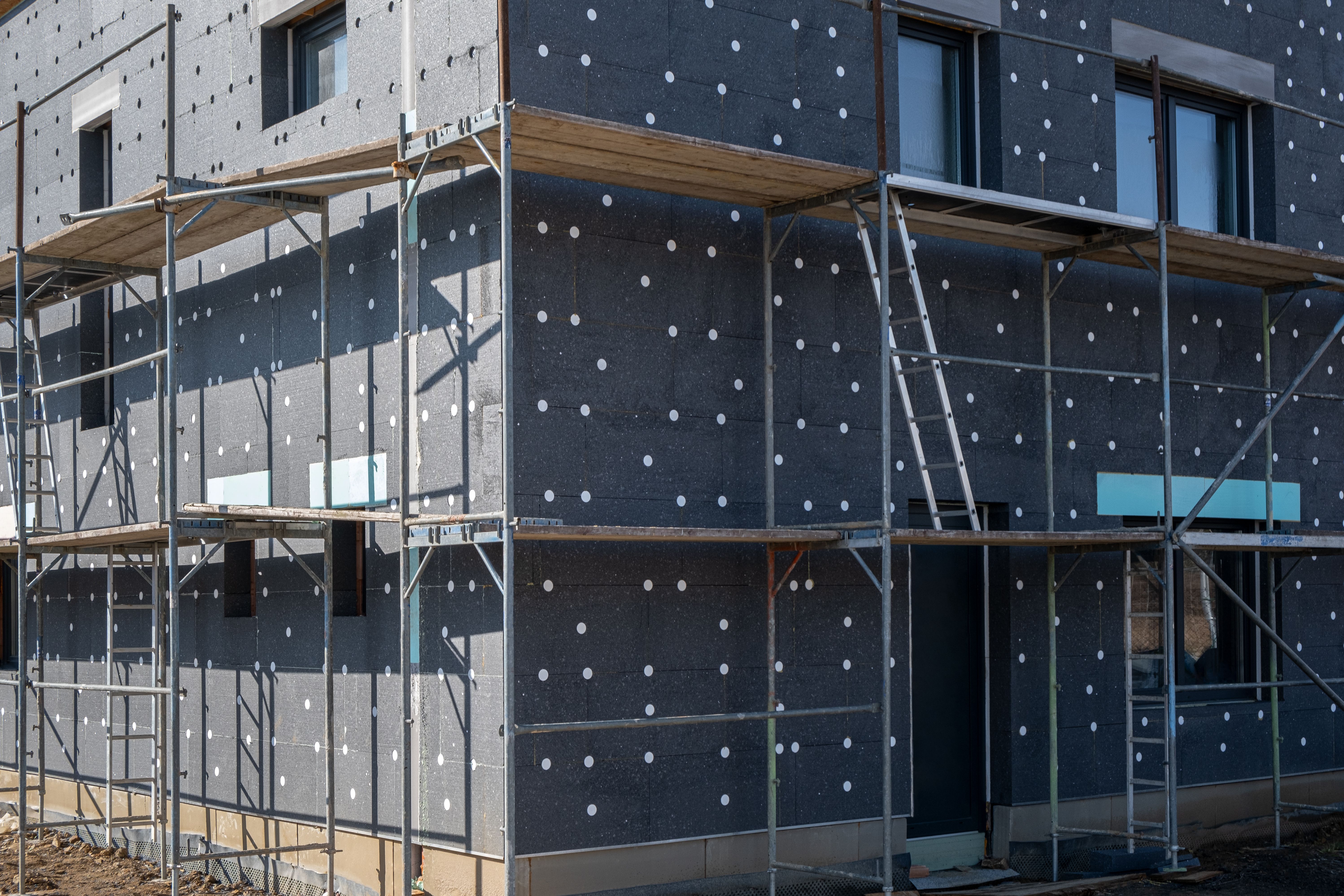 modern thermal insulation materials. building New House in process insulation of the wall of the house with layers Exterior covering in construction site. modern thermal insulation materials. building New House in process insulation of the wall of the house with layers Exterior covering in construction site.