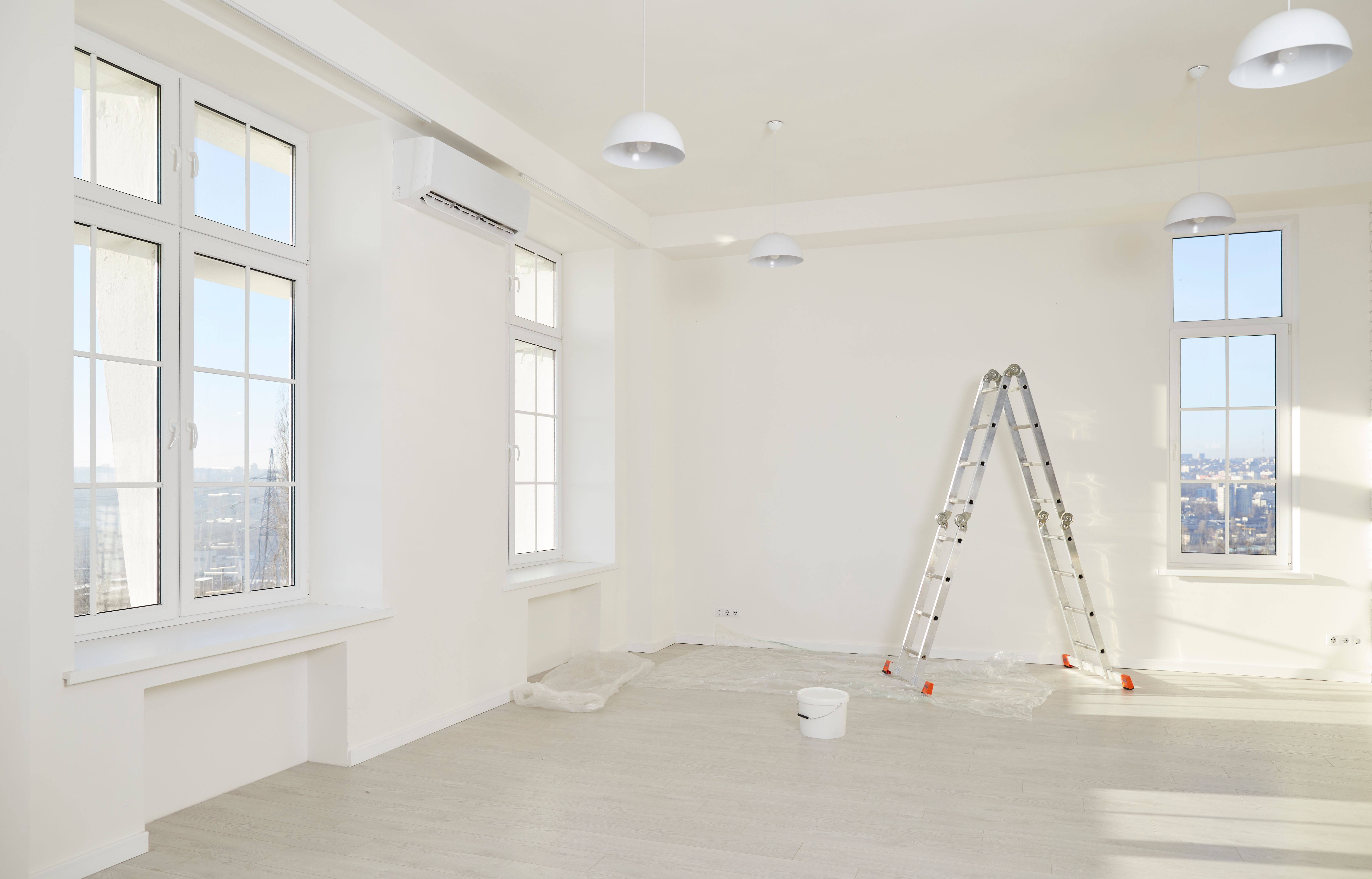 Interior of newly renovated apartment with white walls, new windows, ladder and paint can