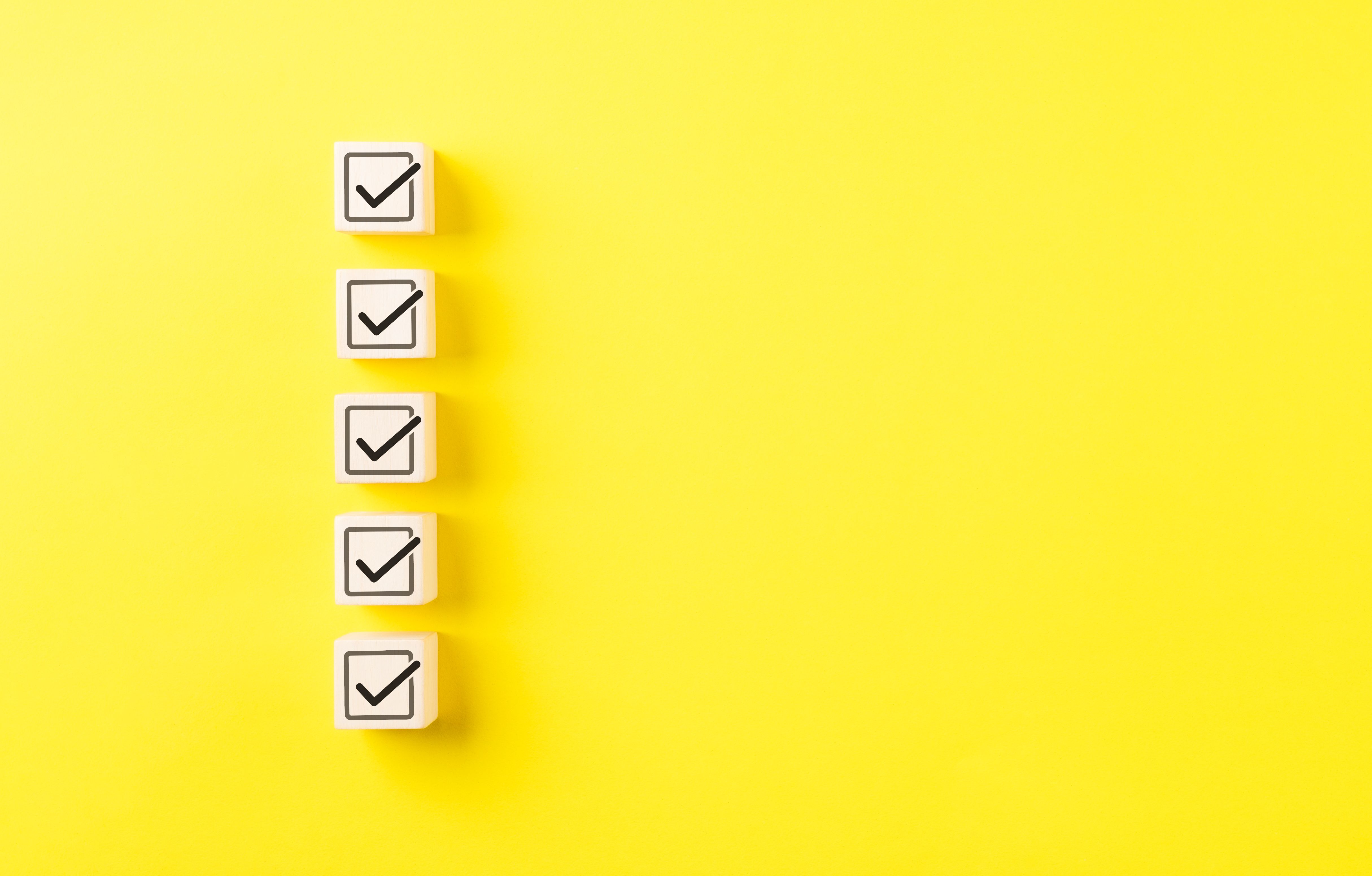 Checklist concept. Correct sign tick check mark on wooden block with copy space for the checklist on yellow background. Business survey questionnaire, Exam test process, filling digital form online,