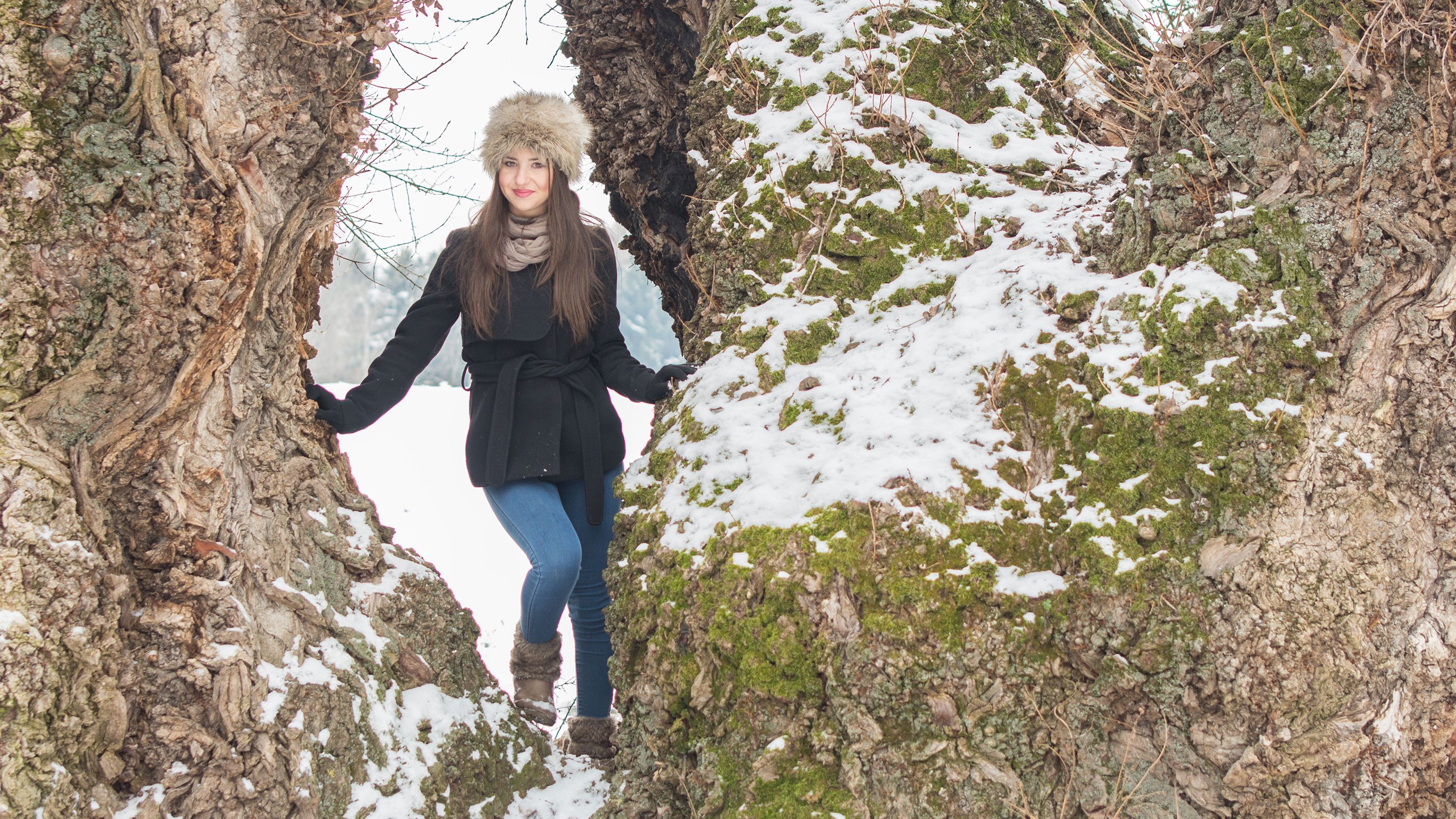 Beautiful Caucasian girl in snow near tree