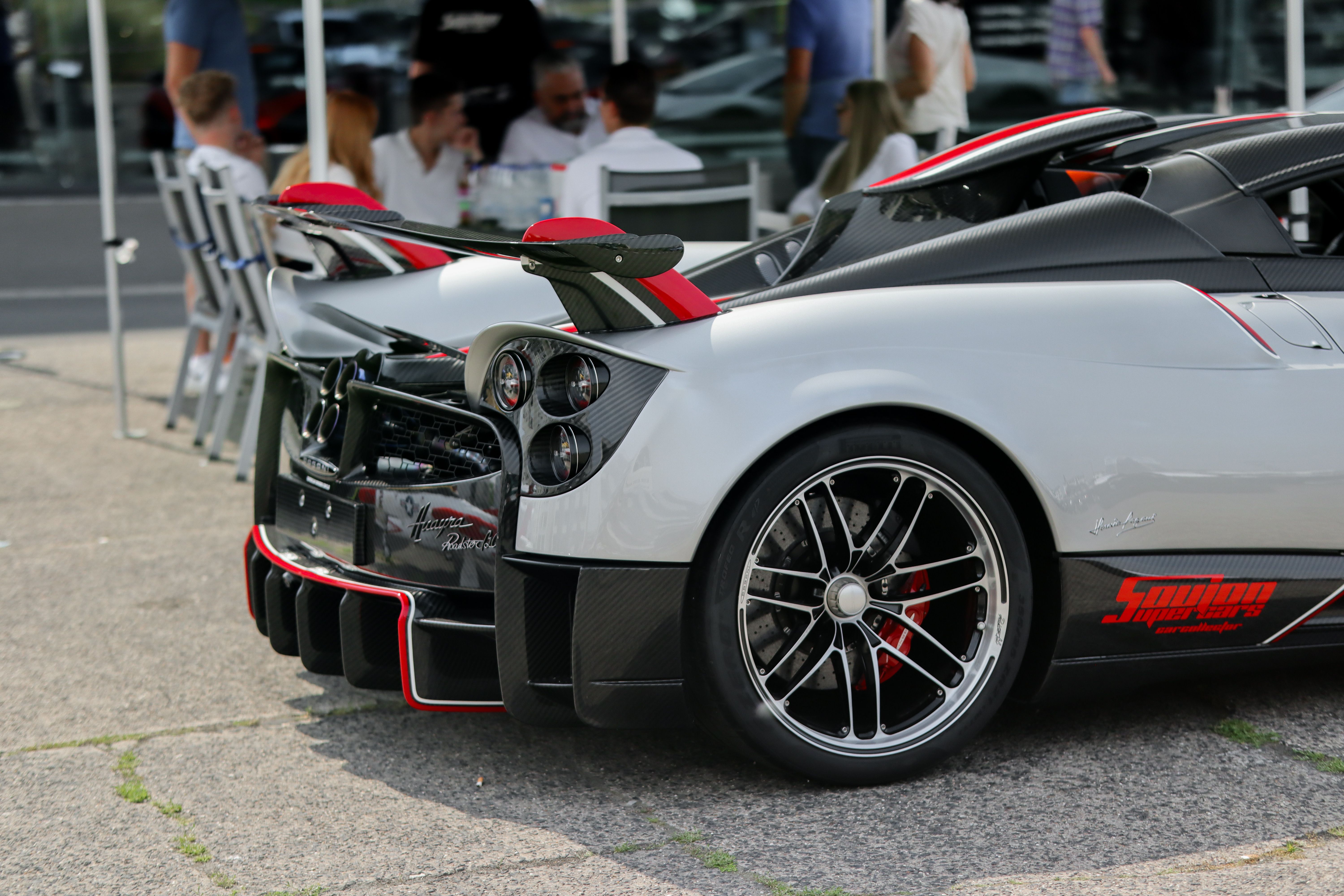Glossy Pagani Huayra Roadster BC 1.20 parked on a paved surface with bright red alloy wheels