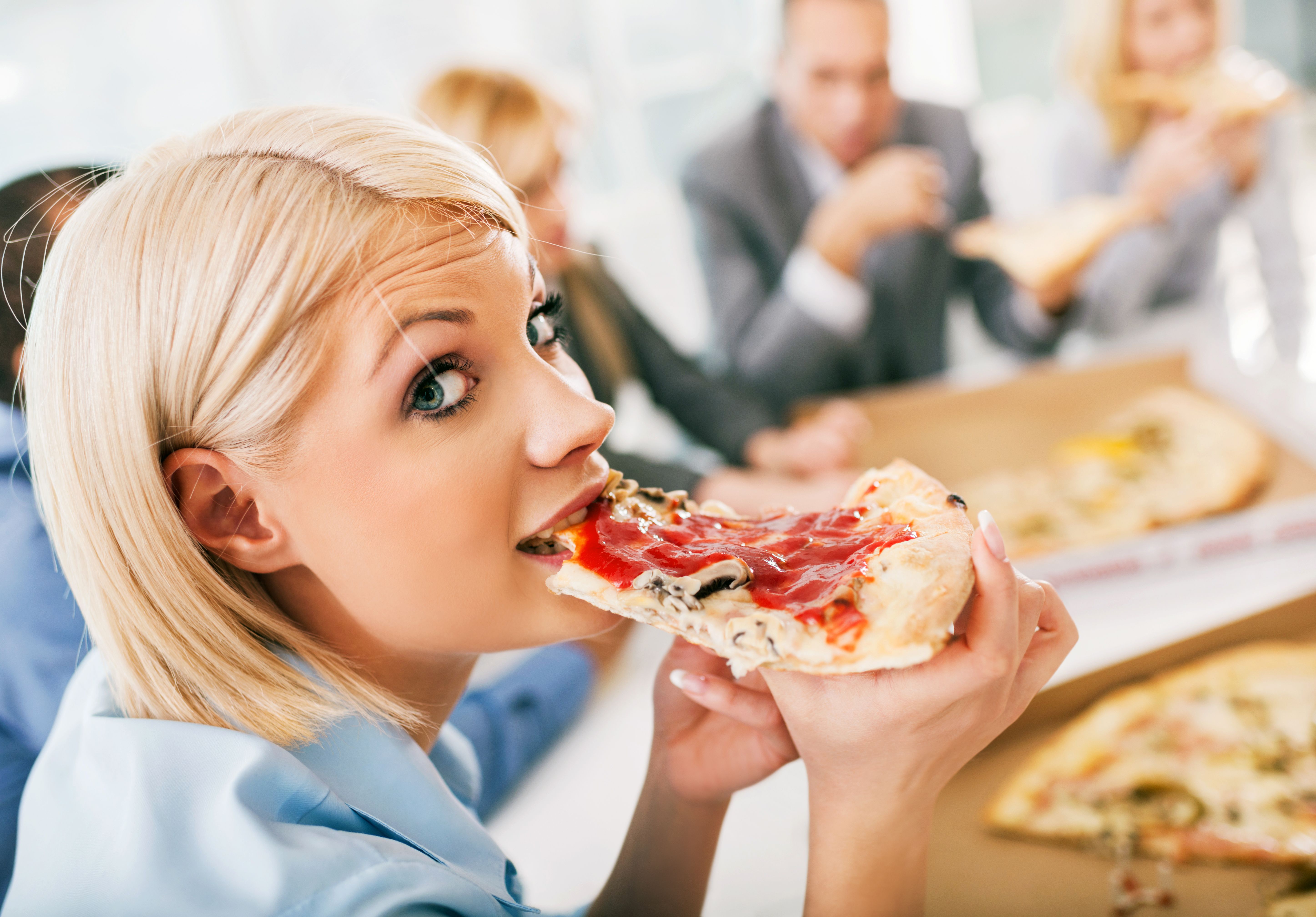 Businesswoman eating pizza on a meeting.