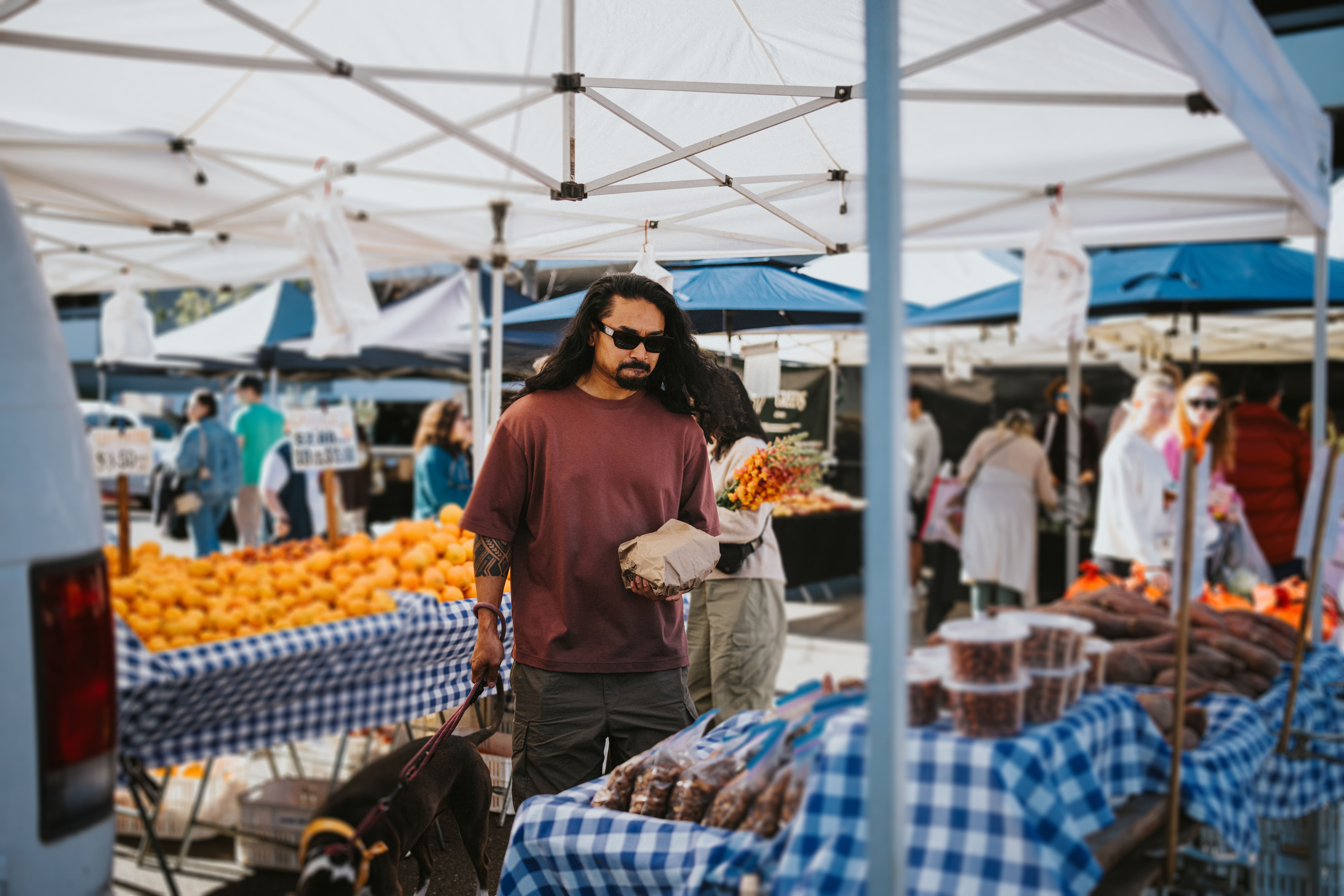 Man with pet dog shopping for produce at the farmer's market Man with pet dog shopping for produce at the farmer's market