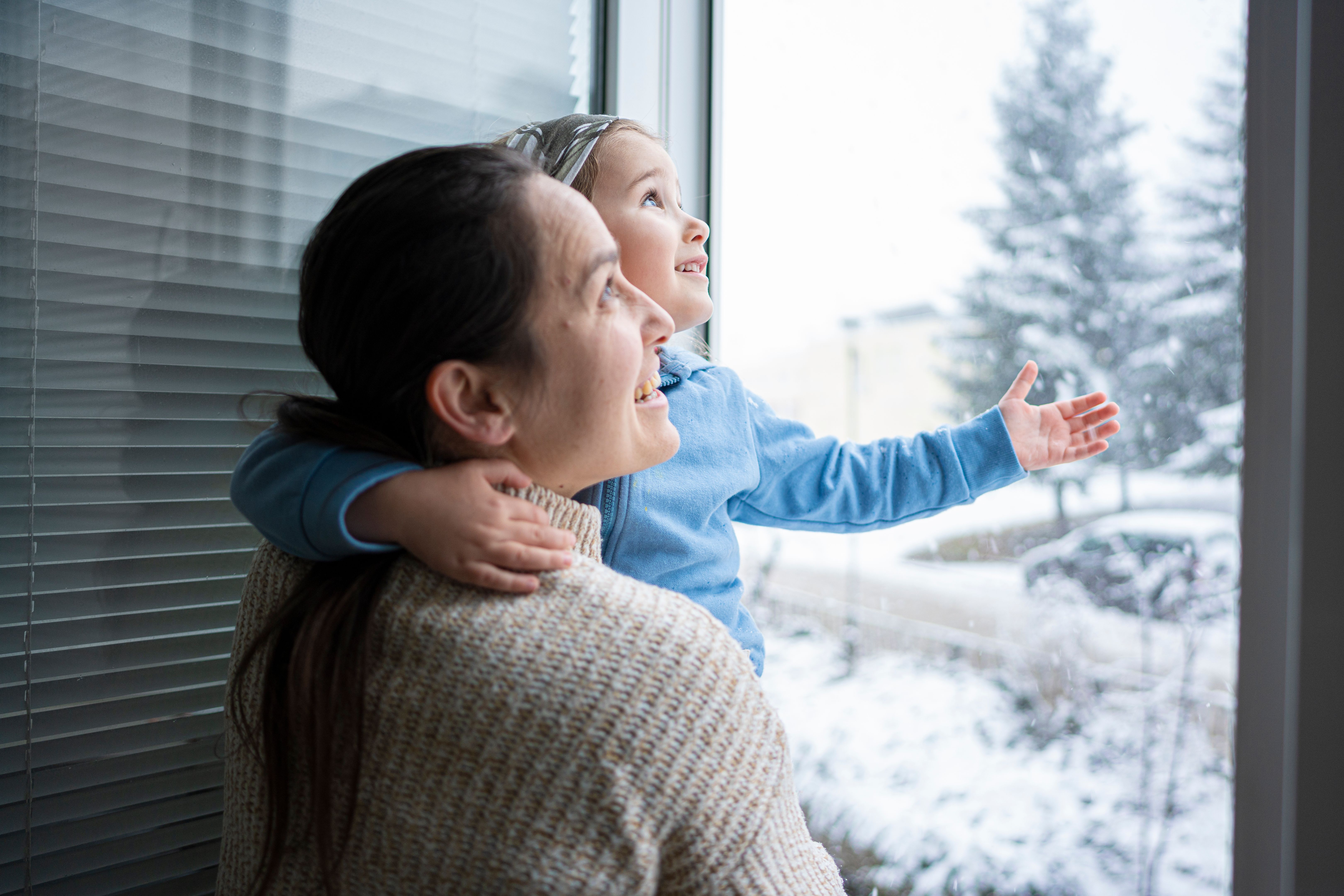 Happy Family Enjoying Snowfall From Window. Winter Mood