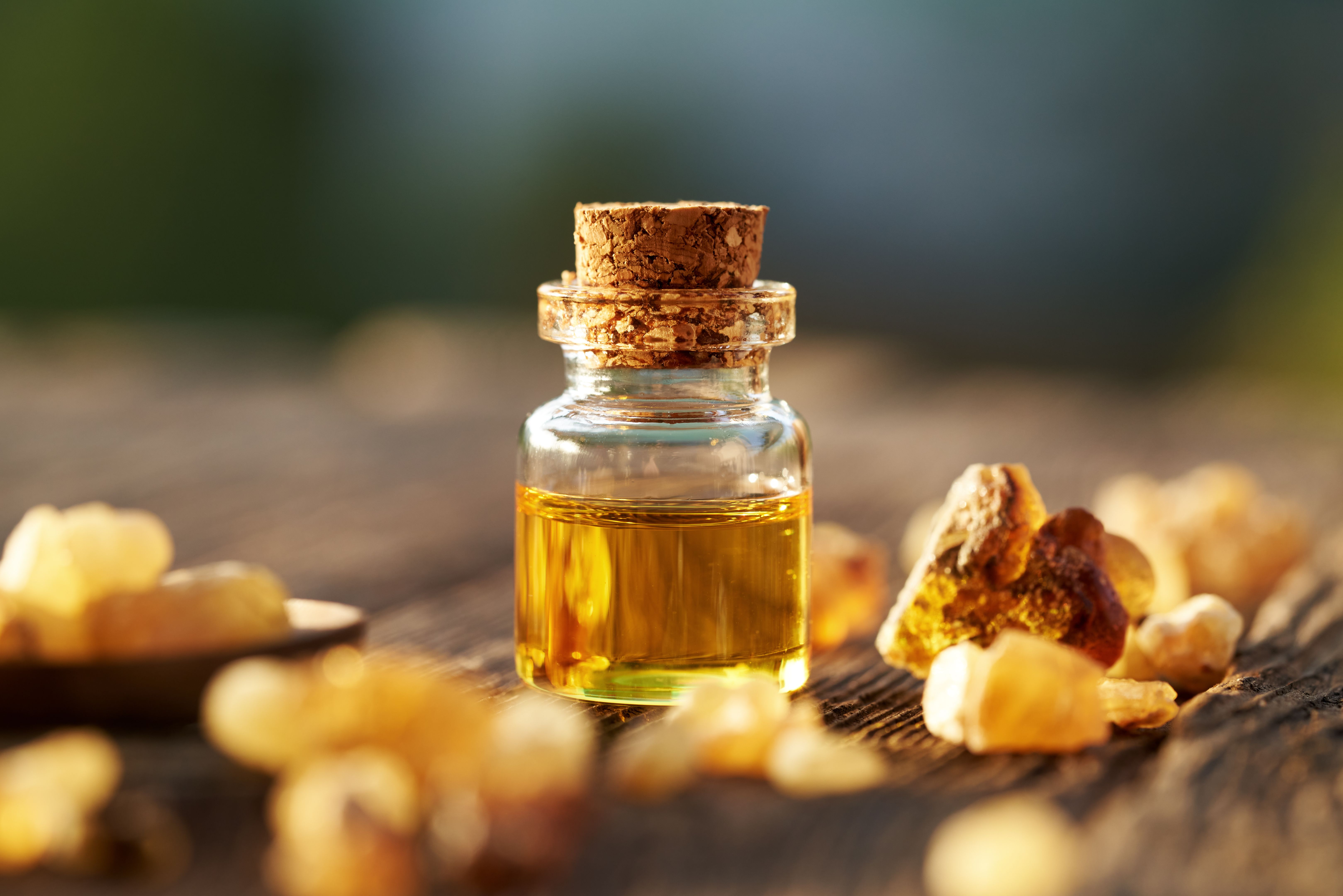 Frankincense essential oil in a glass bottle with boswellia resin on a table