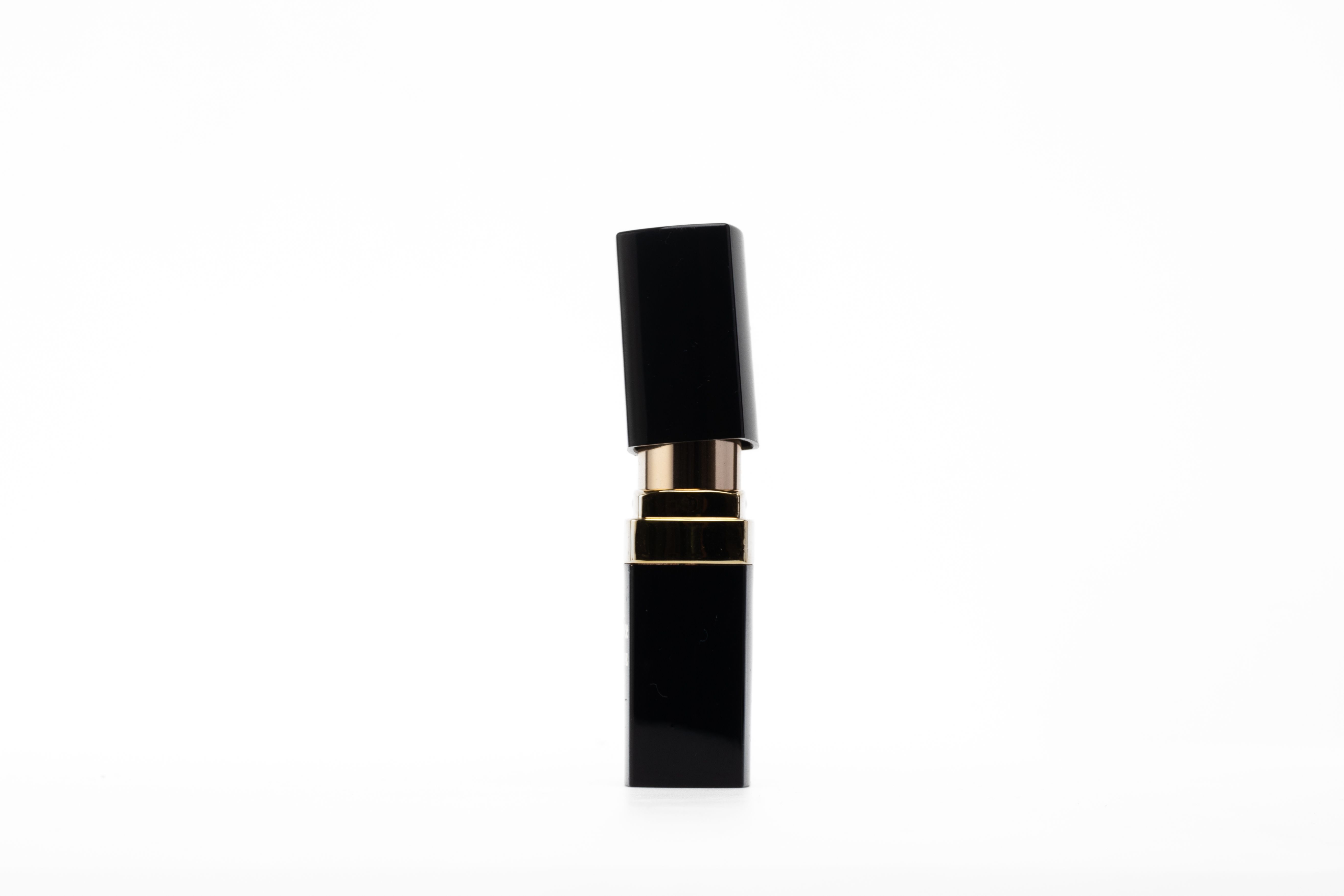 A sleek, black and gold lipstick tube stands upright against a clean white background, showcasing its elegant design