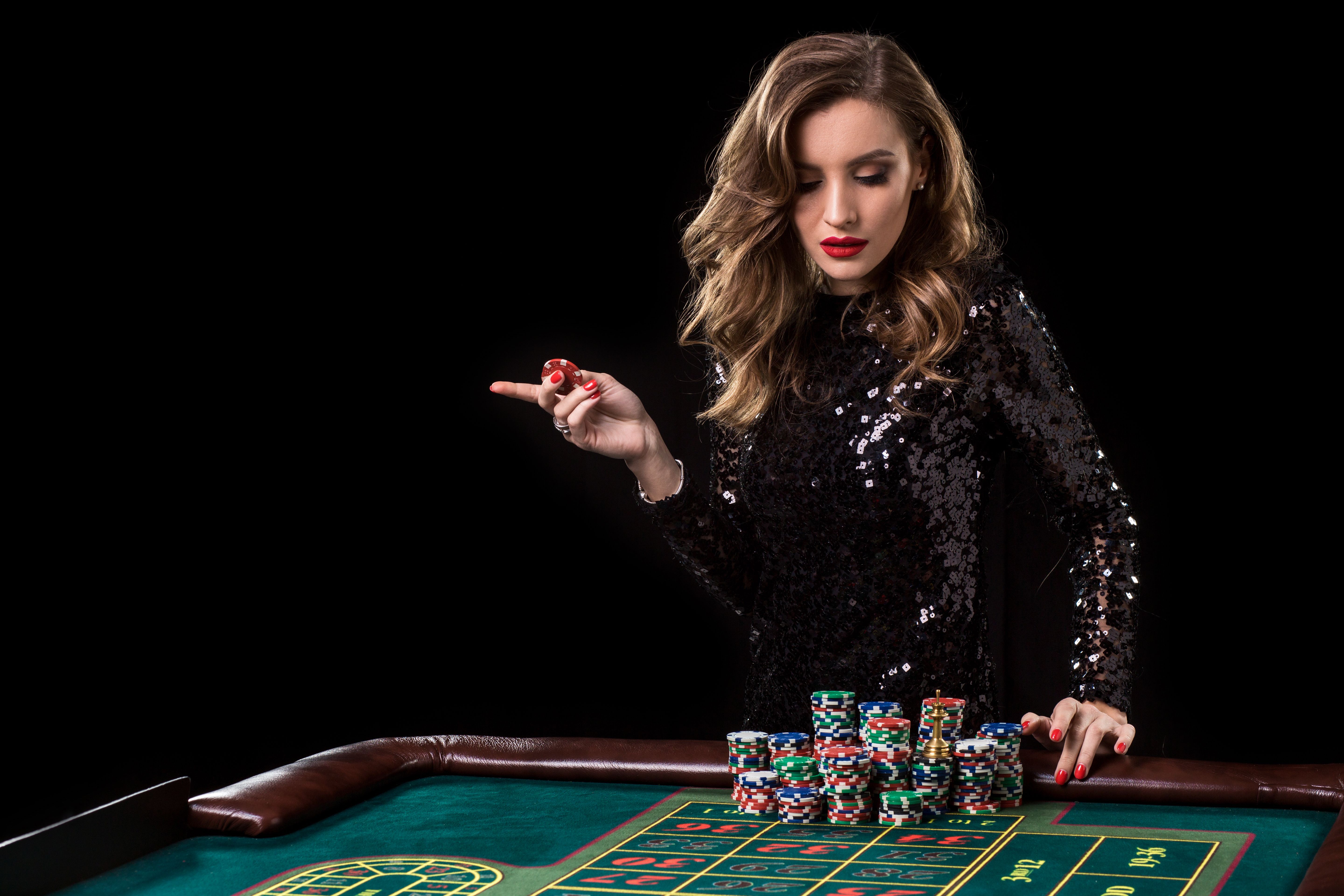 Woman playing in casino. Woman stakes piles of chips playing rou