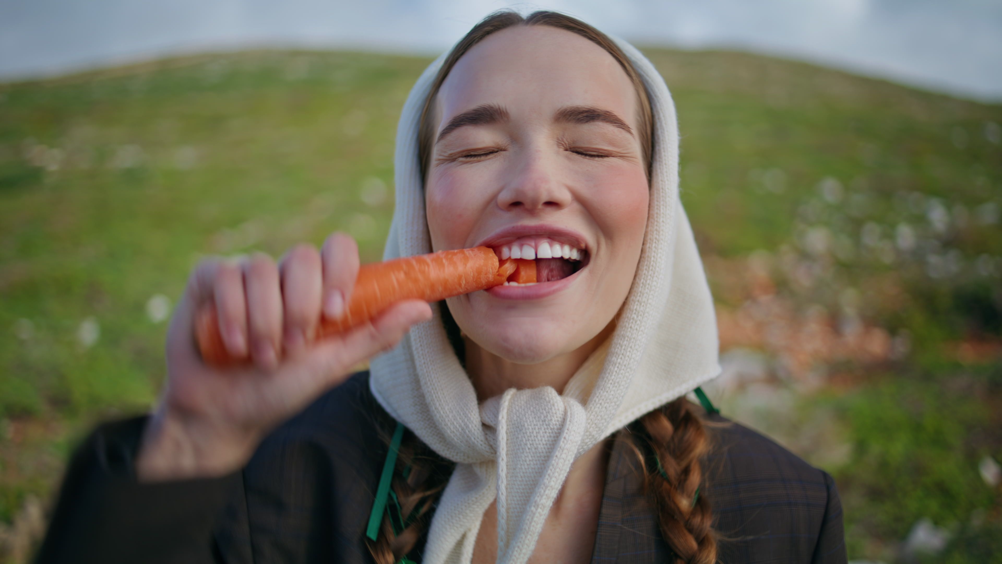Woman biting fresh carrot healthy vegetable closeup. Happy vegetarian enjoying