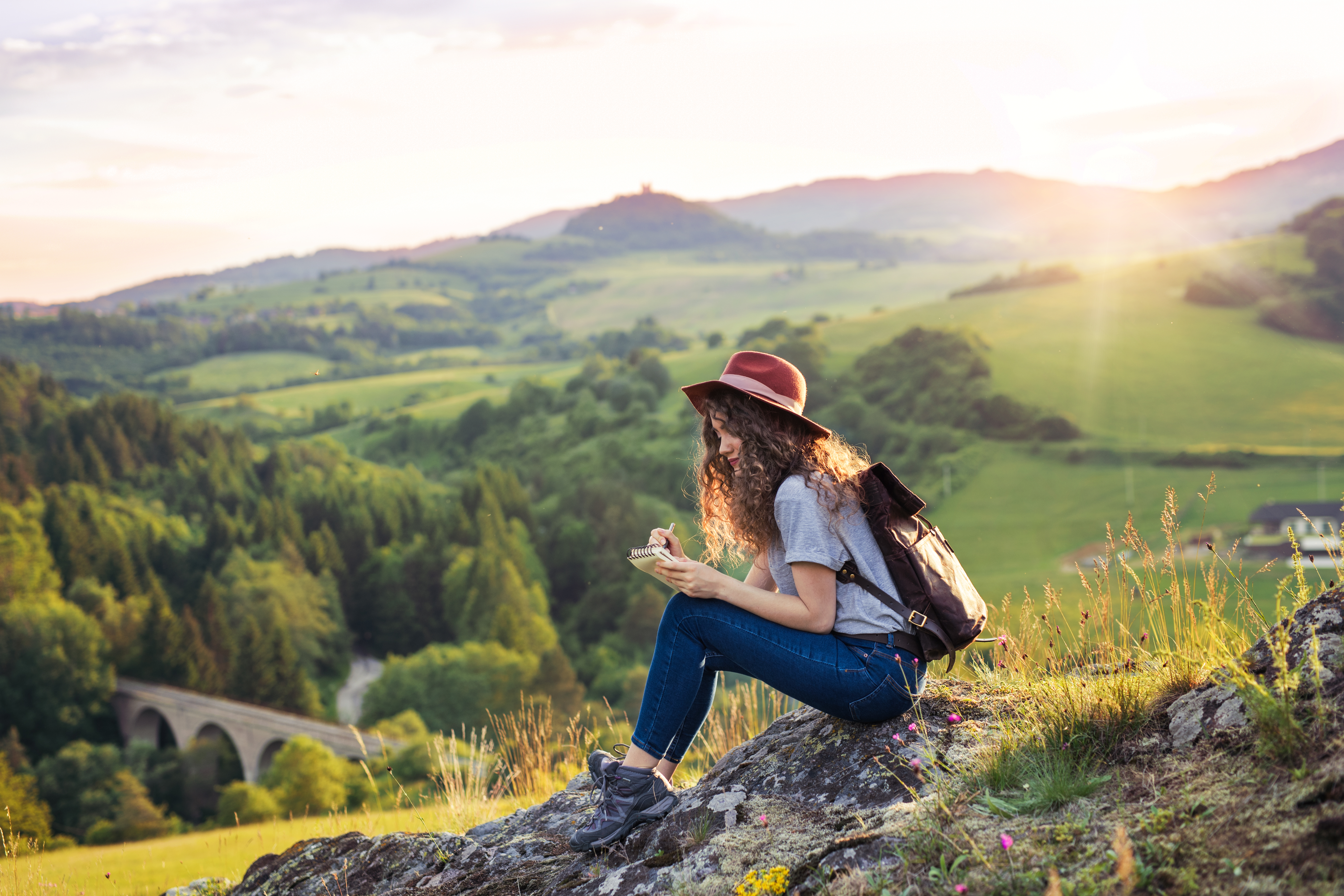 Young tourist woman traveller with backpack sitting in nature, writing notes. Young tourist woman traveller with backpack sitting in nature, writing notes.