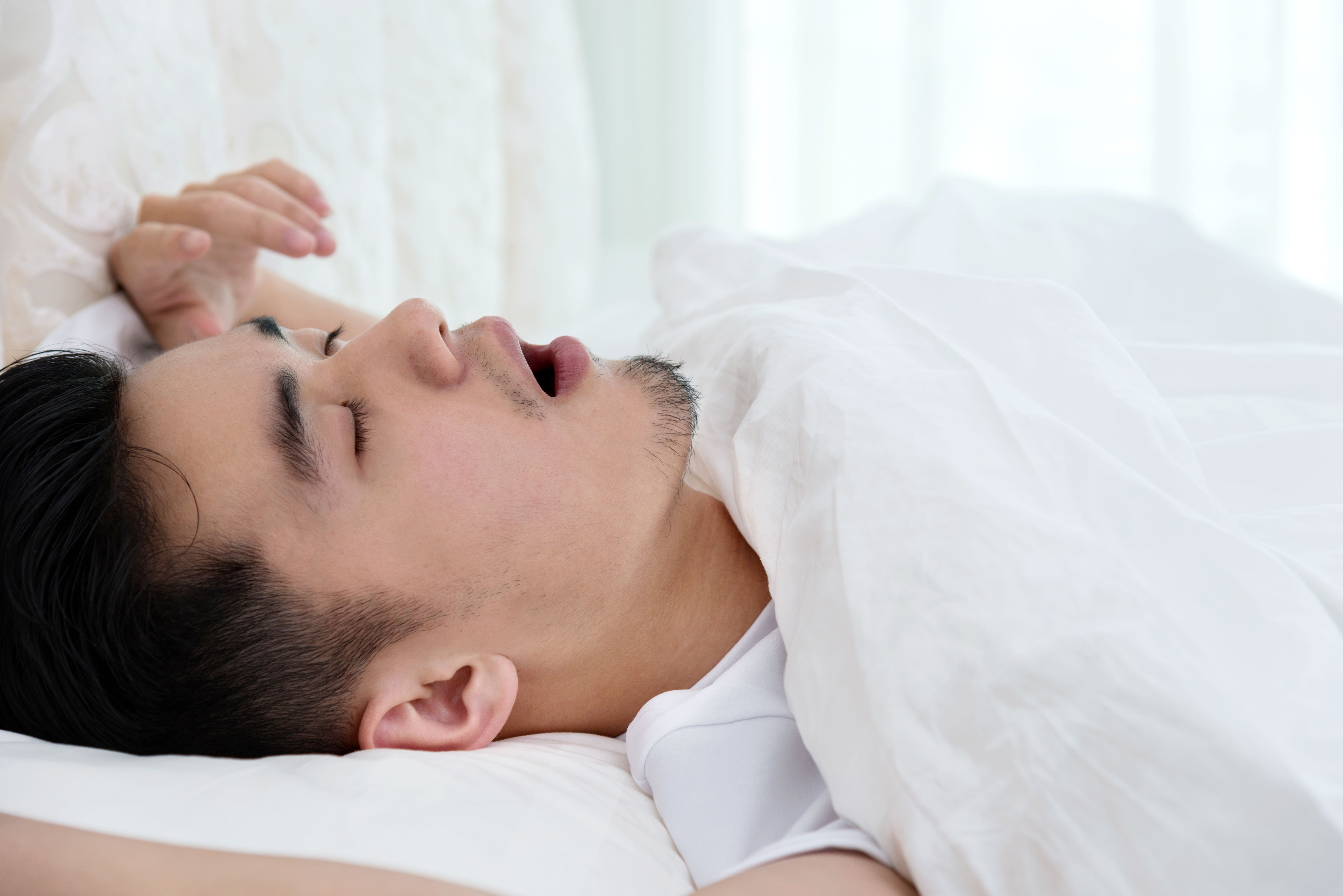 Young man asleep in bed snoring