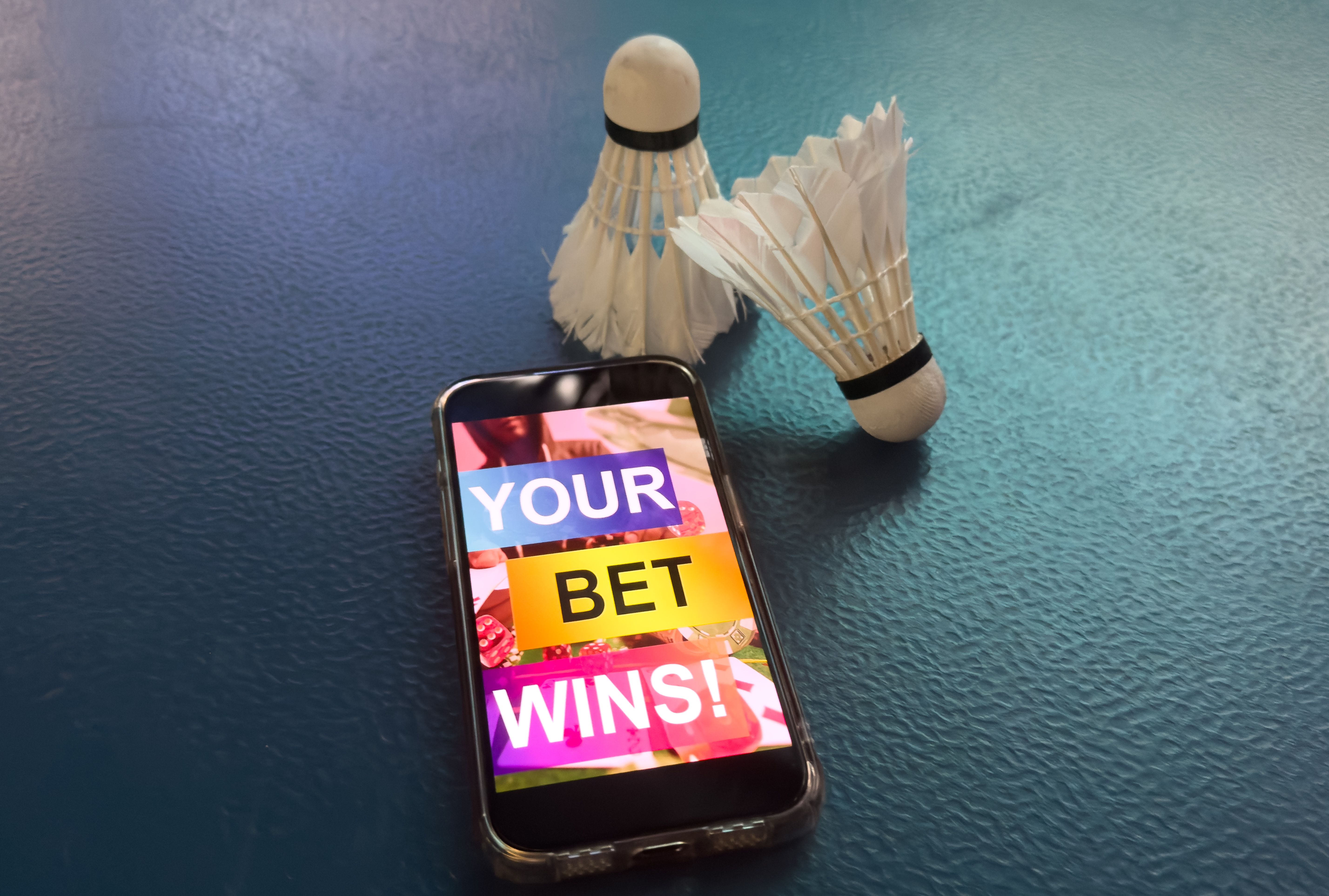 a badminton racket and a smartphone with sports bets