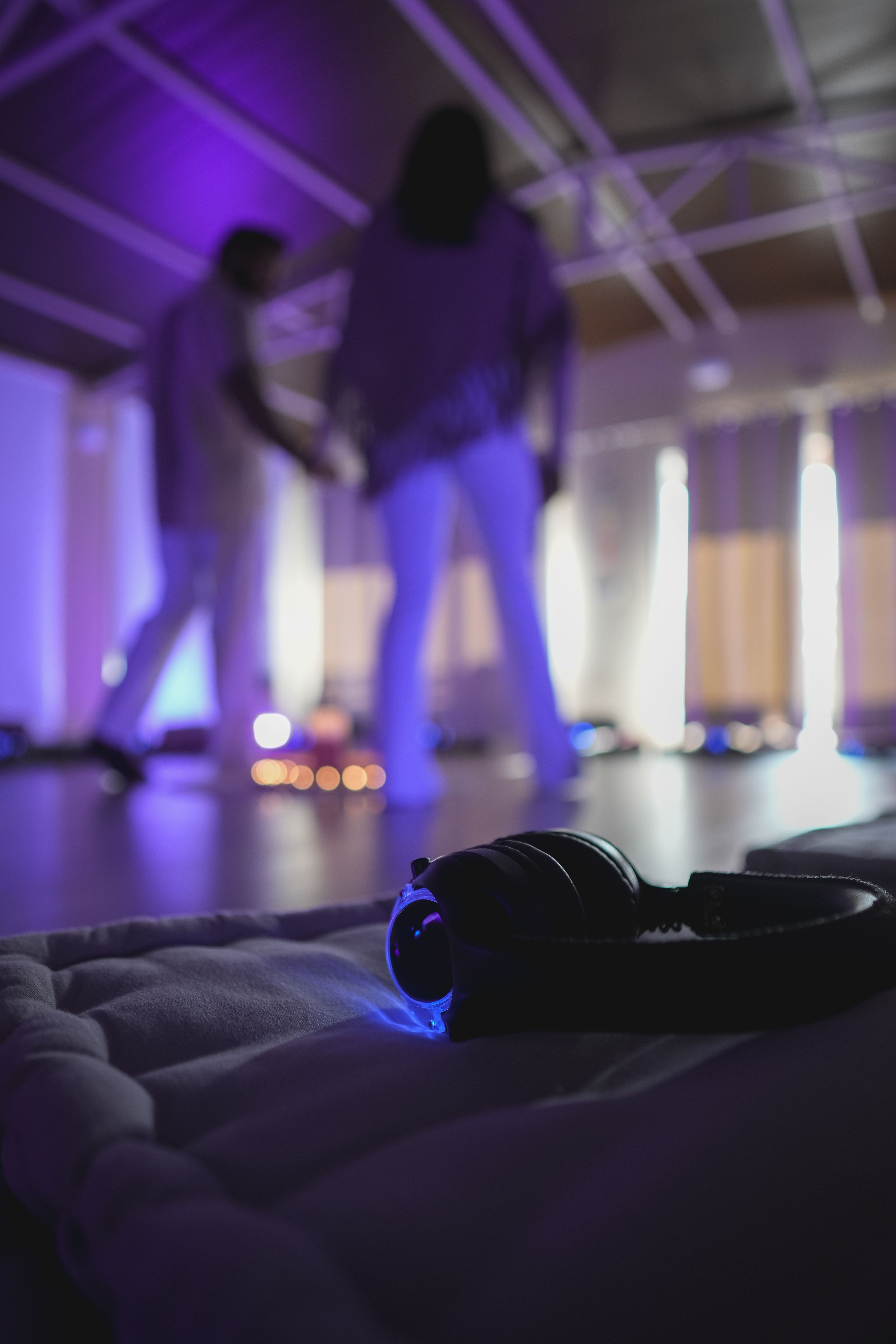 Wireless headphones resting on a cushion during a breathwork session with blurred people in background