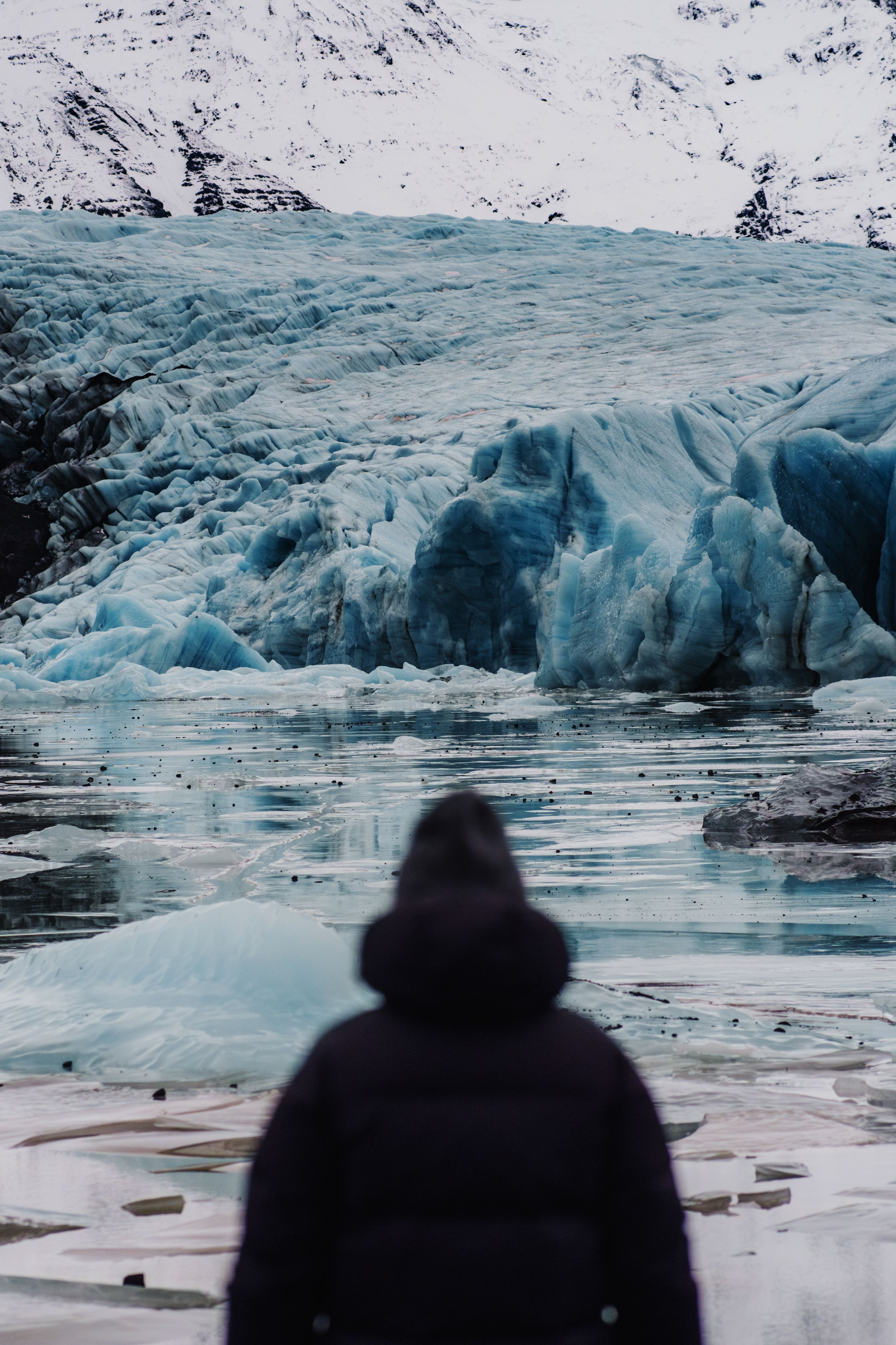 Person admiring the massive ice formations of Svinafellsjokull glacier in Iceland.