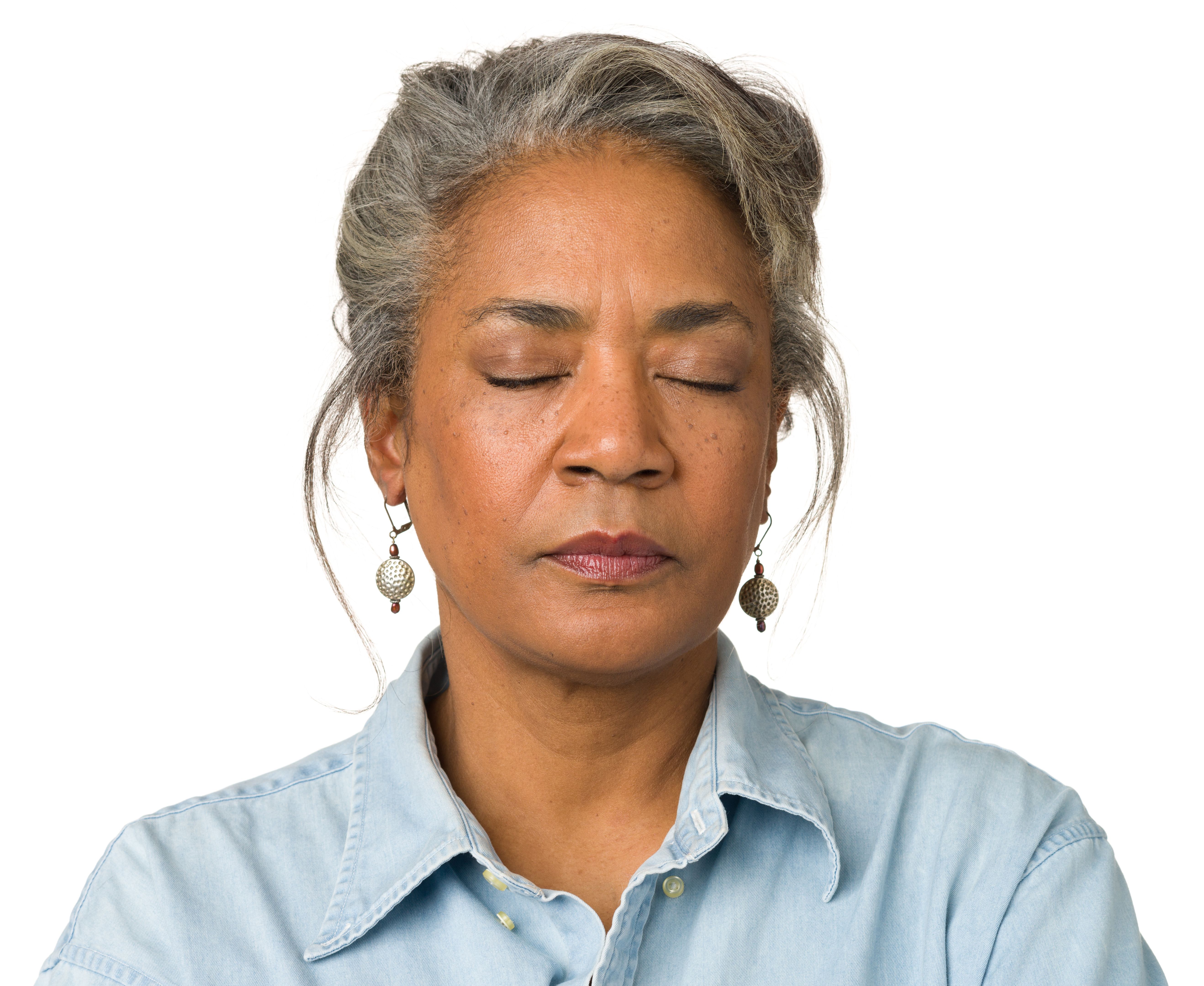Gray haired woman wearing droplet earrings with eyes closed