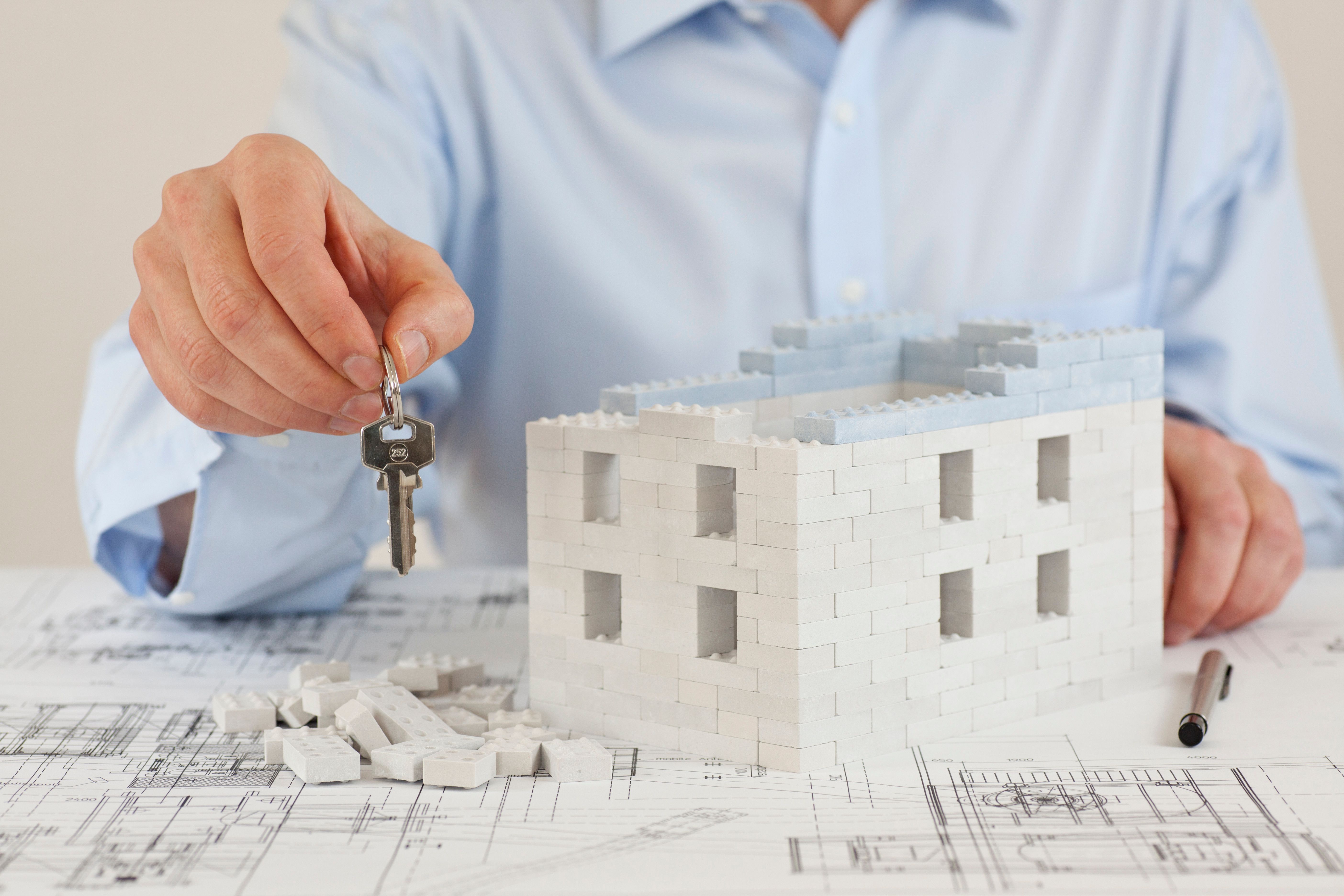 Architetto presenta le chiavi di una casa sul piano di costruzione