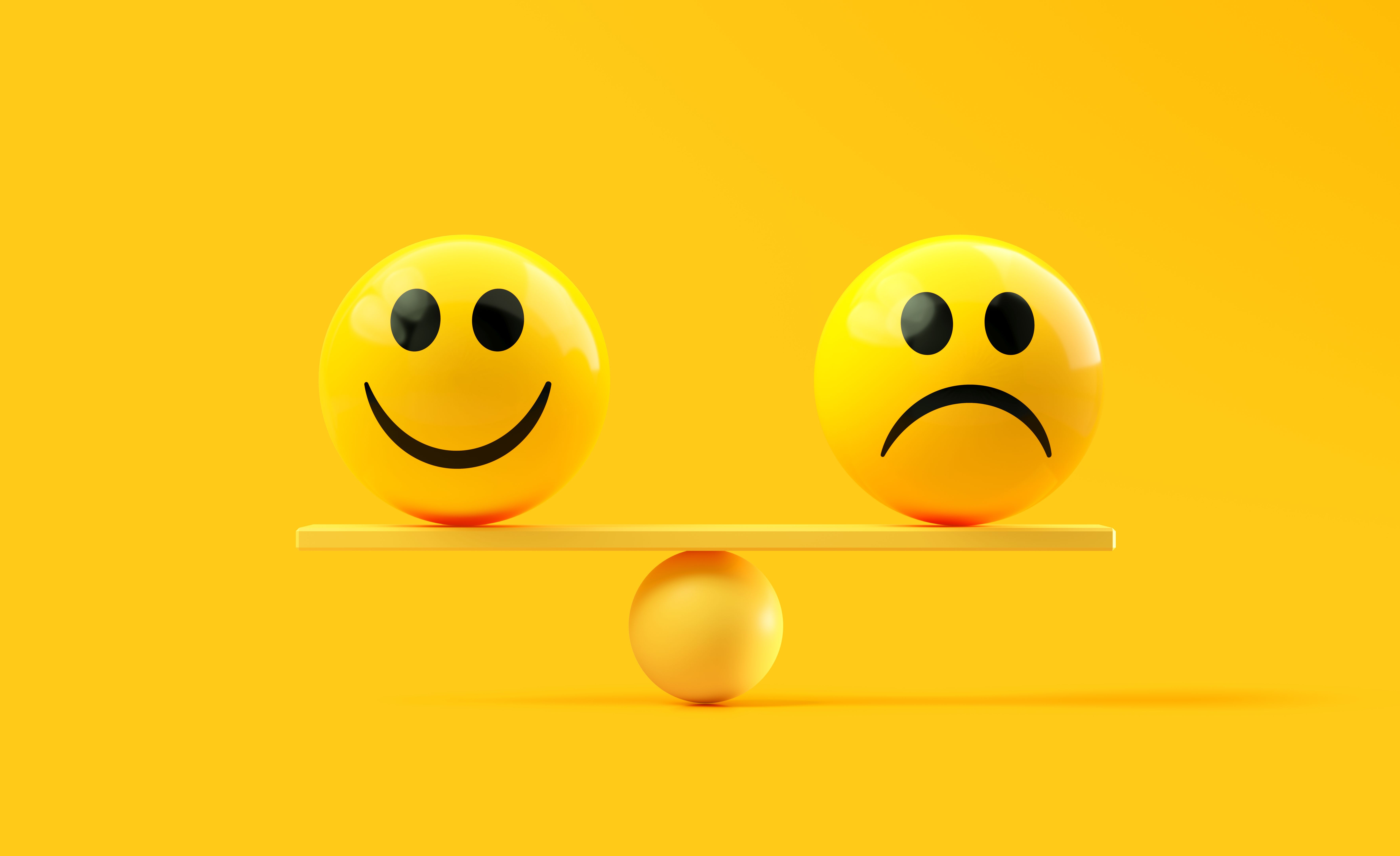 Yellow Spheres Textured With Happy And Sad Face Emojis On A Yellow Seesaw Over Yellow Background