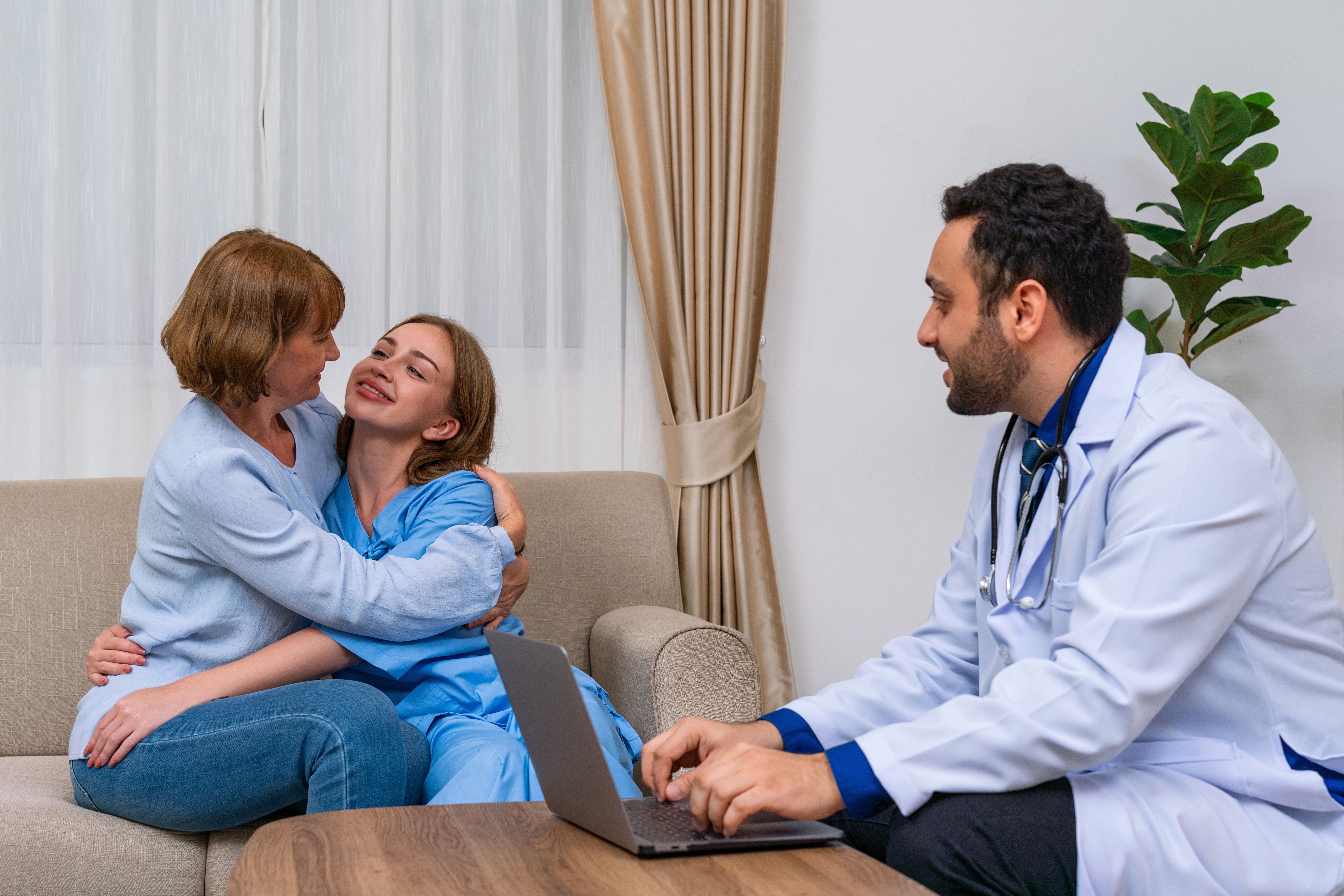 Doctor discussing medical condition with a female patient and her mother using a computer laptop